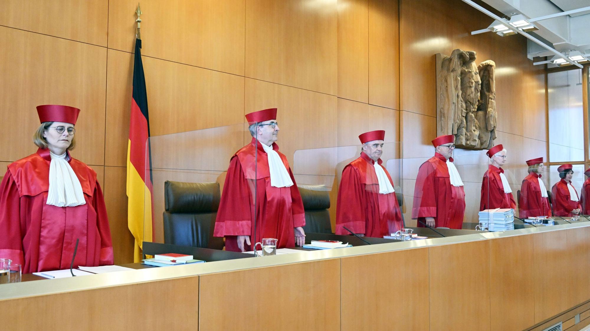 Richterinnen und Richter des Bundesverfassungsgerichts stehen in einem Gerichtssaal.