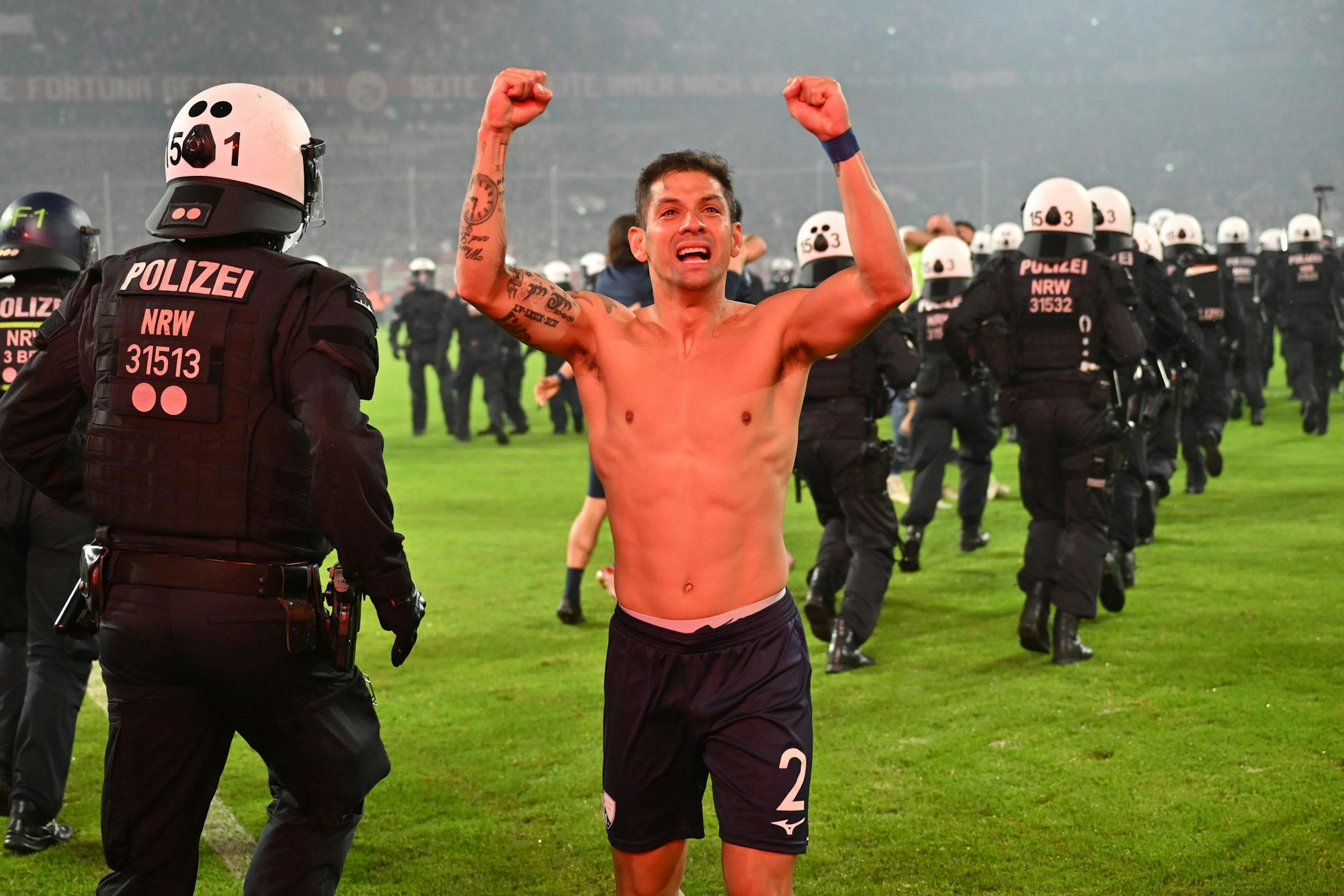 Bochums Cristian Gamboa jubelt nach dem gewonnenen Elfmeterschießen. Hinter ihm marschieren zahlreiche Polizisten ein.