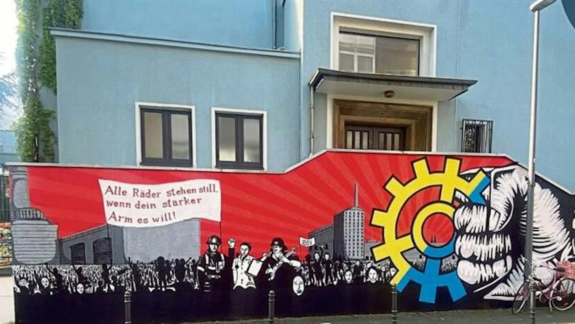 Blick auf ein Wandgemälde mit einem Zahnrad und Personen.