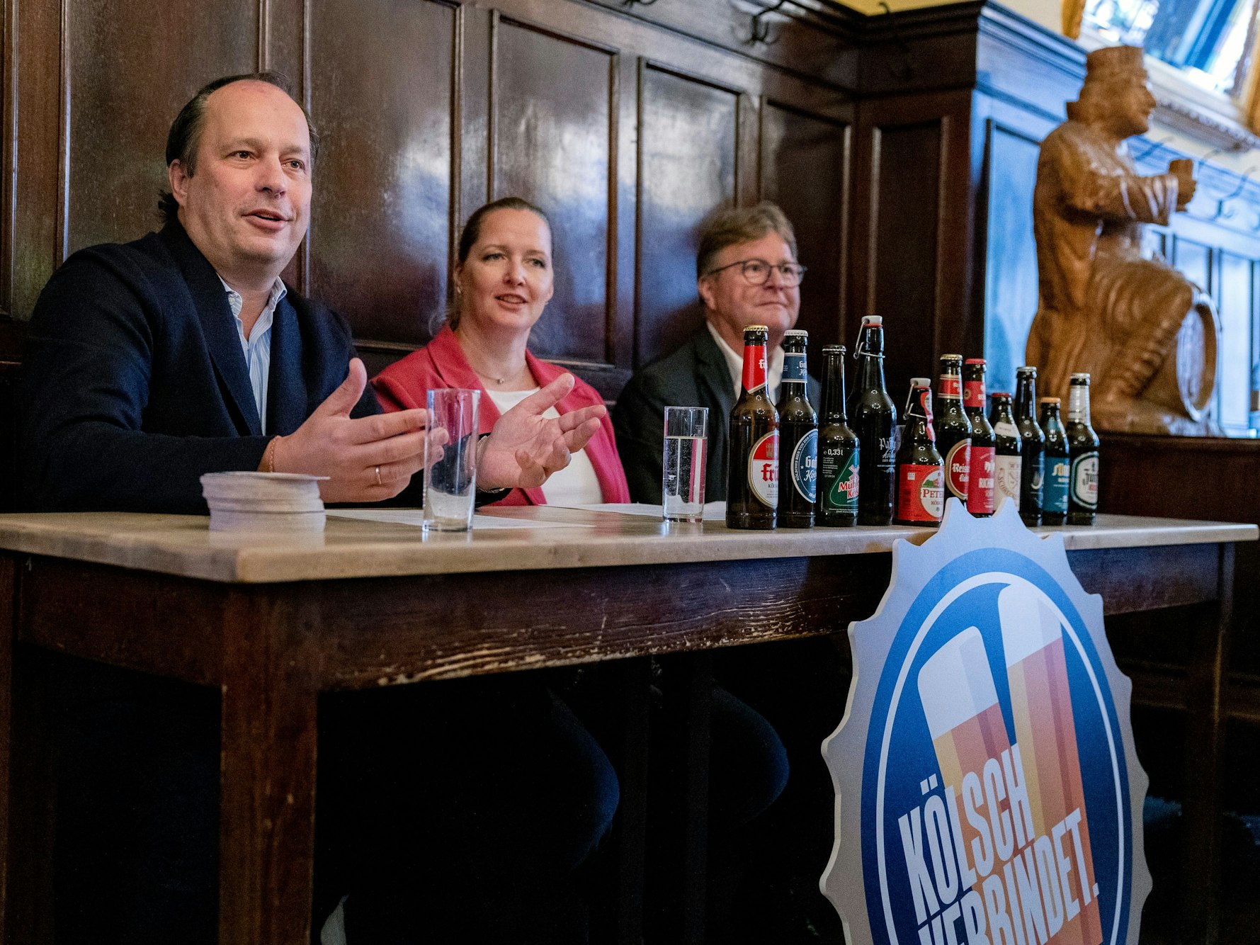 Heinrich Philipp Becker, Melanie Schwartz und Alexander Rolff an einem Pult in einer Kölner Brauerei.