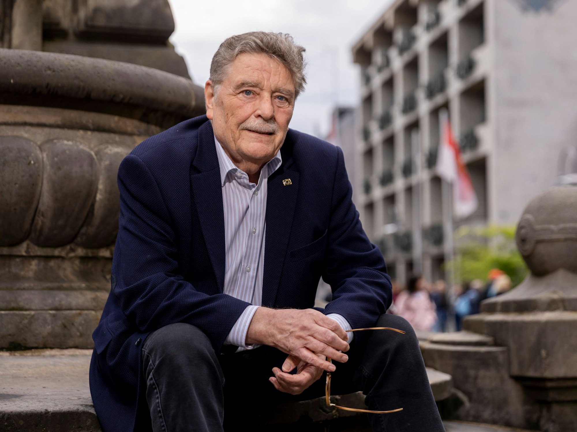 Fritz Schramma sitzt auf einer Treppe in Köln und schaut in die Kamera.