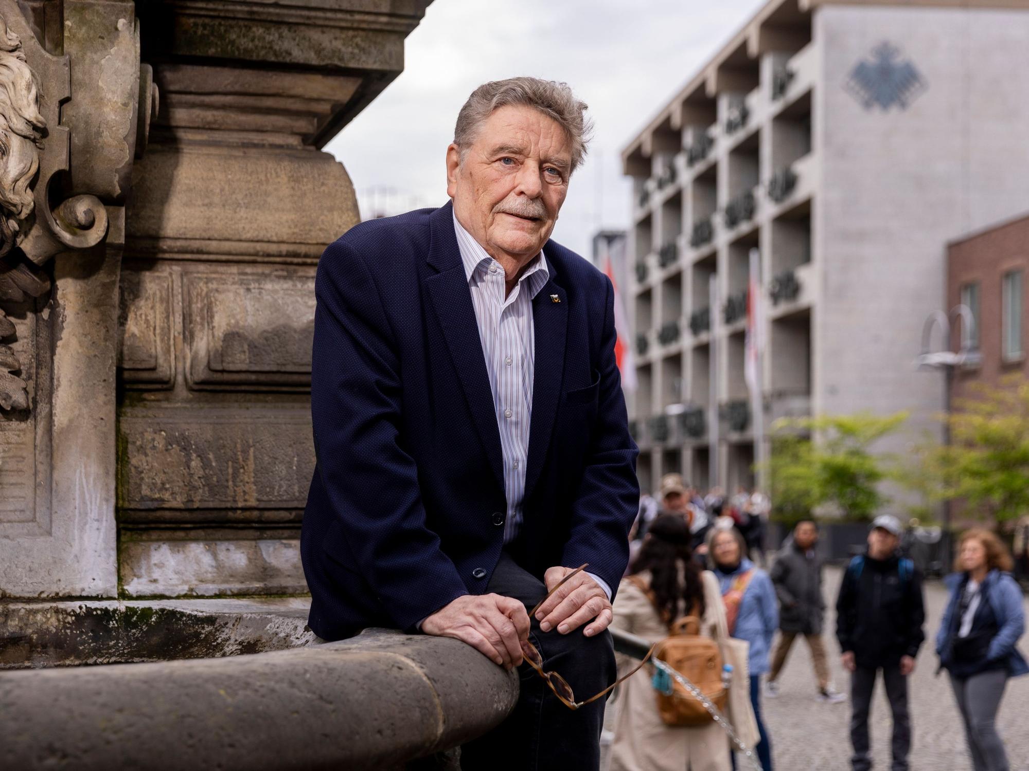 Fritz Schramma sitzt leicht angelehnt an einem Brunnen und blickt in die Kamera.