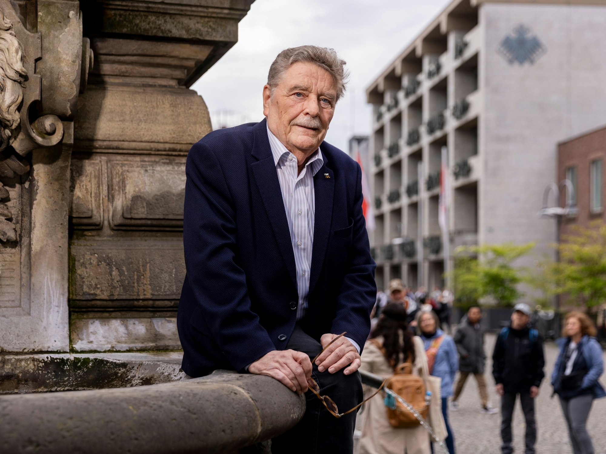 Fritz Schramma sitzt leicht angelehnt an einem Brunnen und blickt in die Kamera.