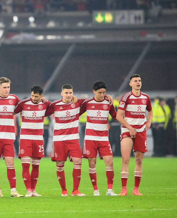 Die Spieler von Fortuna Düsseldorf stehen beim Elfmeterschießen im Relegations-Rückspiel gegen den VfL Bochum Arm in Arm zusammen.