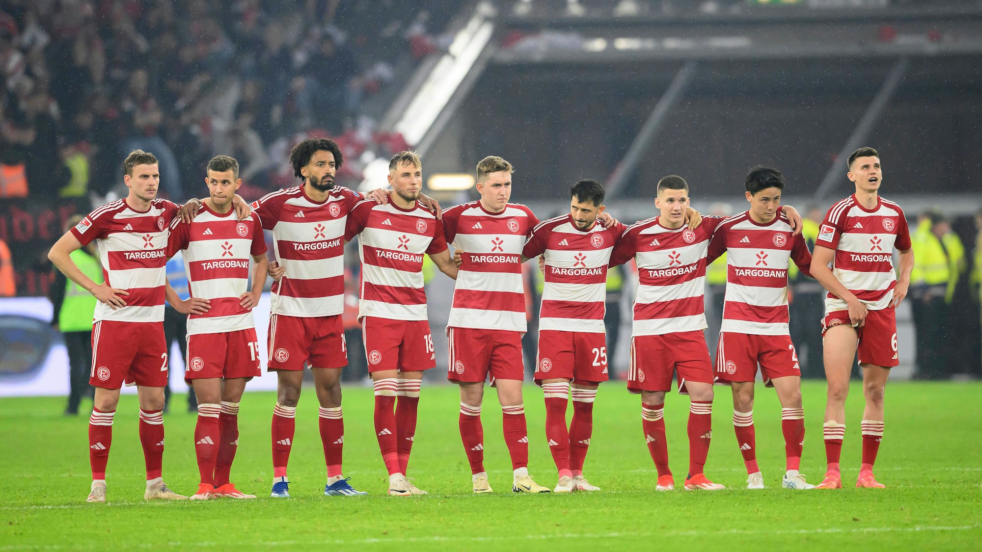 Die Spieler von Fortuna Düsseldorf stehen beim Elfmeterschießen im Relegations-Rückspiel gegen den VfL Bochum Arm in Arm zusammen.