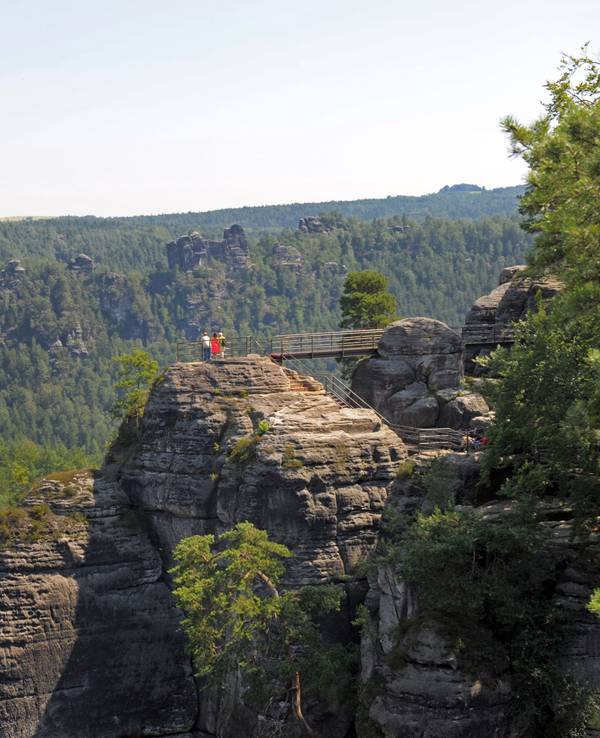 Menschen stehen in der Sächsischen Schweiz bei Rathen auf den Stegen der Felsenburg Neurathen. Von hier bietet sich ein guter Blick auf die Sandsteinformationen des Nationalparks.