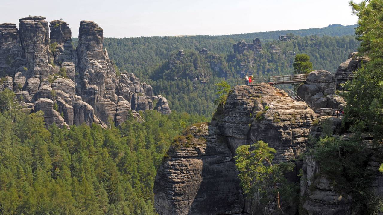 Menschen stehen in der Sächsischen Schweiz bei Rathen auf den Stegen der Felsenburg Neurathen. Von hier bietet sich ein guter Blick auf die Sandsteinformationen des Nationalparks.