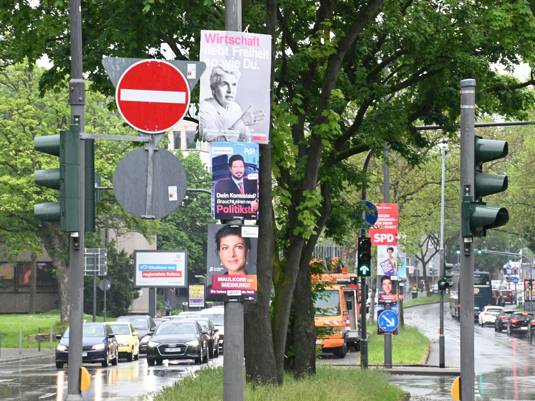 Foto einer Straße mit einigen Autos in Köln, am Straßenrand sind viele Wahlplakate der Europawahl zu sehen.