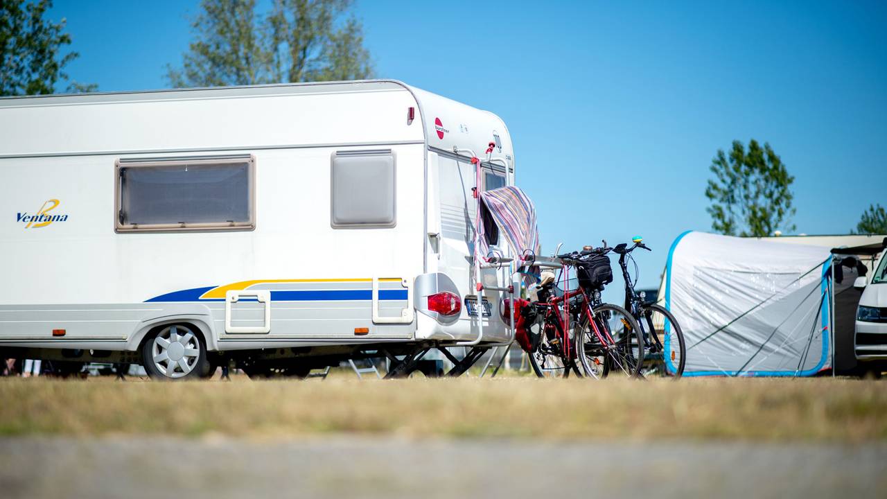 Hier zu sehen: Fahrräder stehen auf einem Campingplatz neben einem Wohnwagen.