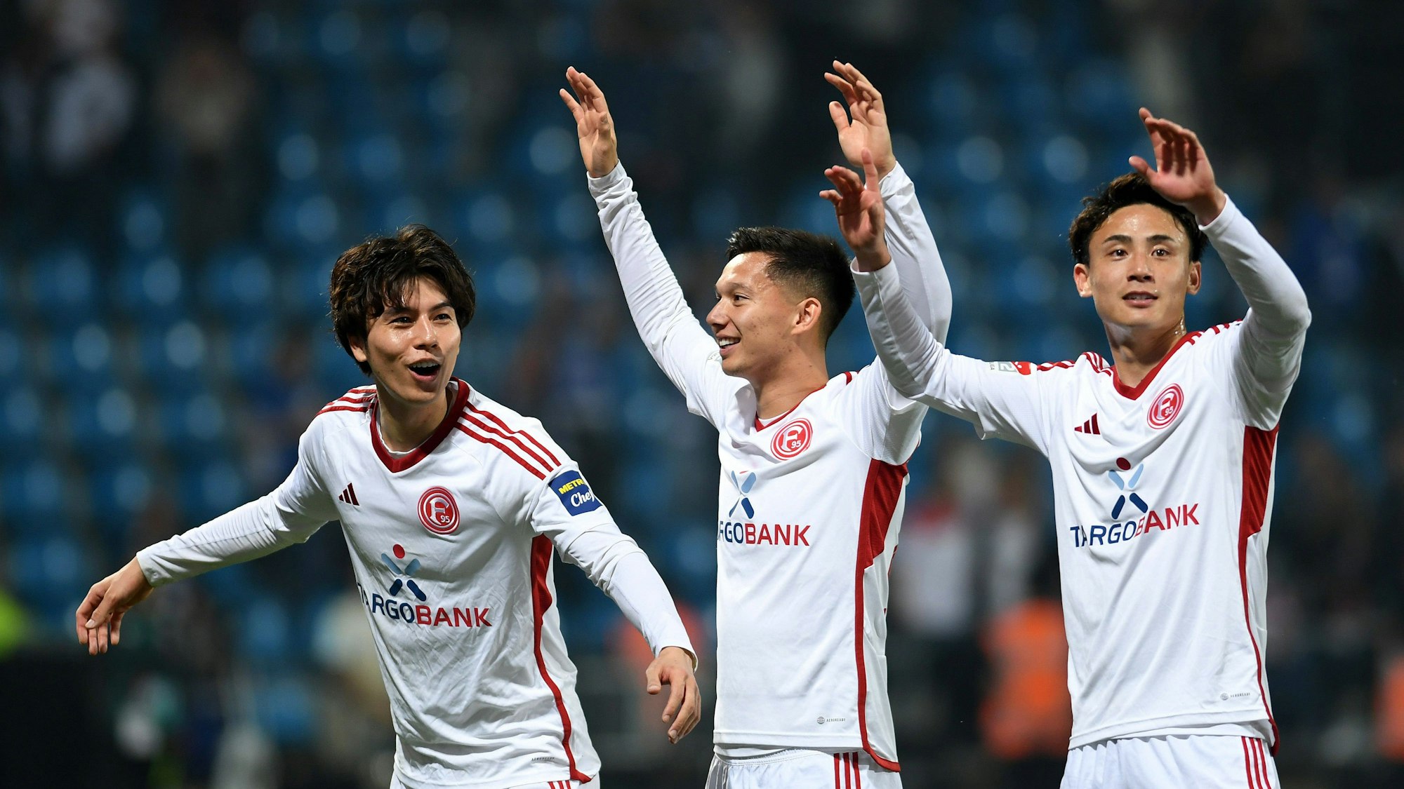 Die Düsseldorf-Profis Ao Tanaka, Shinta Appelkamp und Takashi Uchino jubeln gemeinsam nach dem Relegations-Spiel beim VfL Bochum.