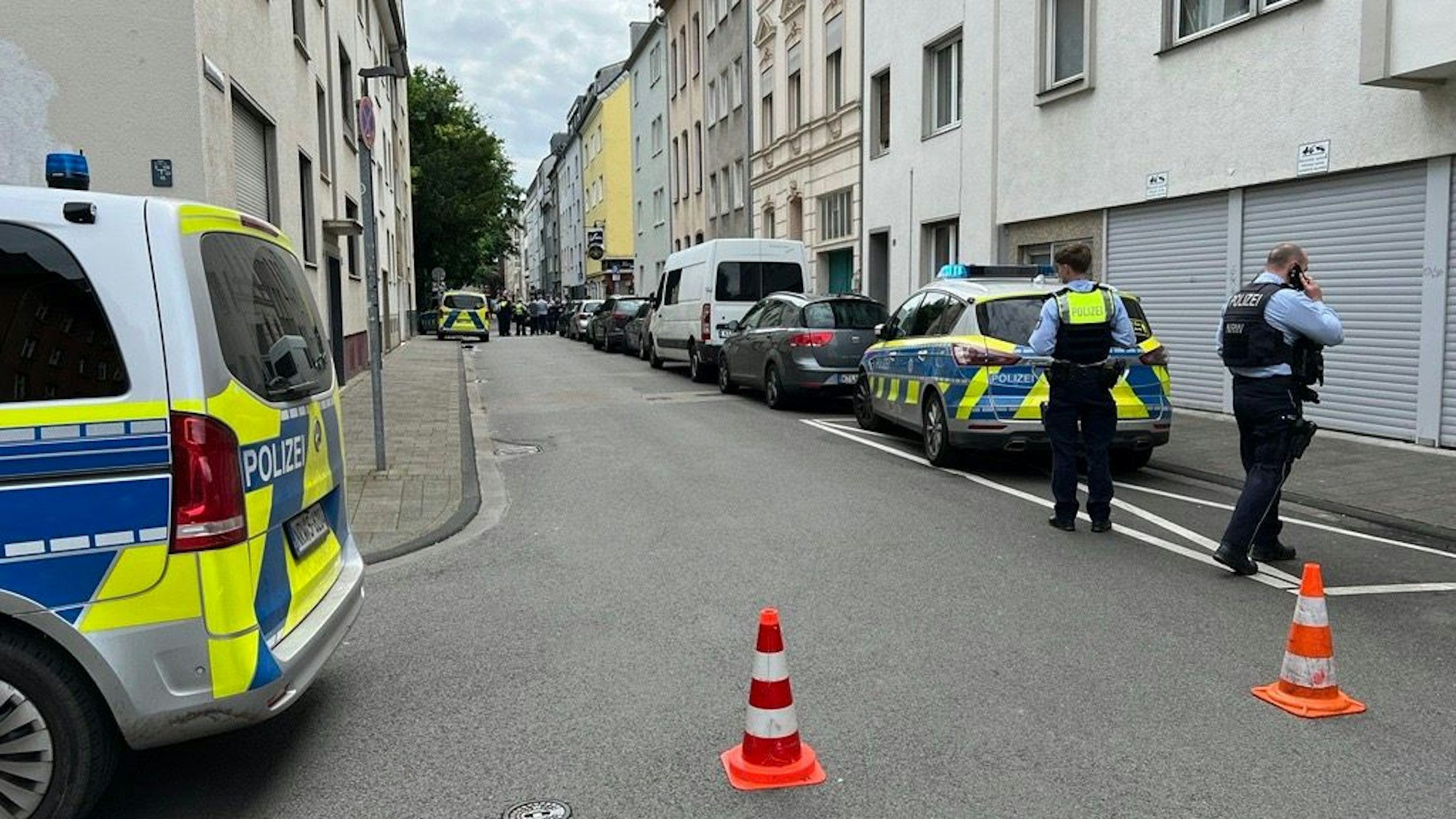 Kräfte der Polizei sowie mehrere Einsatzfahrzeuge stehen in einer Straße.