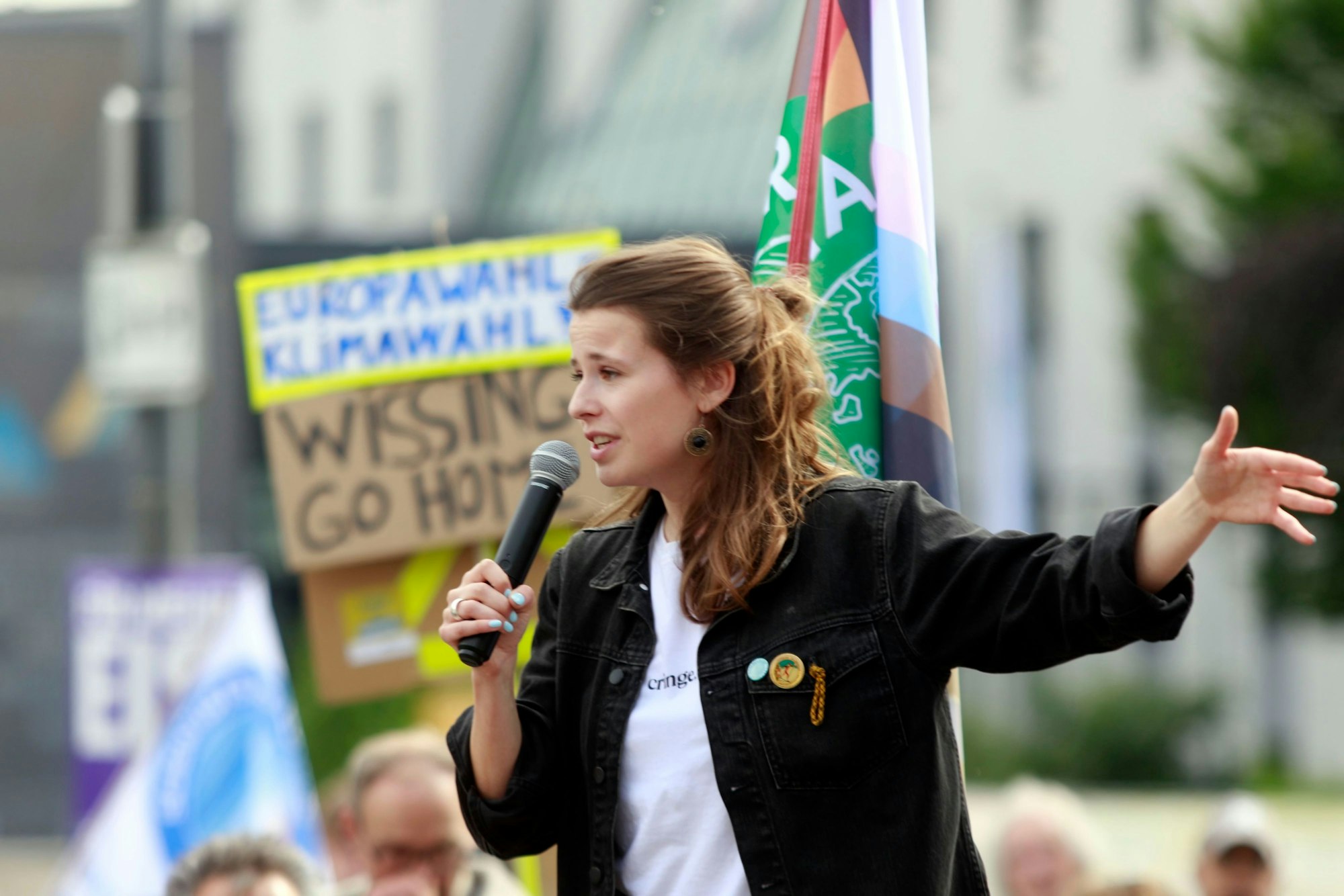 Luisa Neubauer spricht in ein Mikrofon, im Hintergrund Demonstranten.