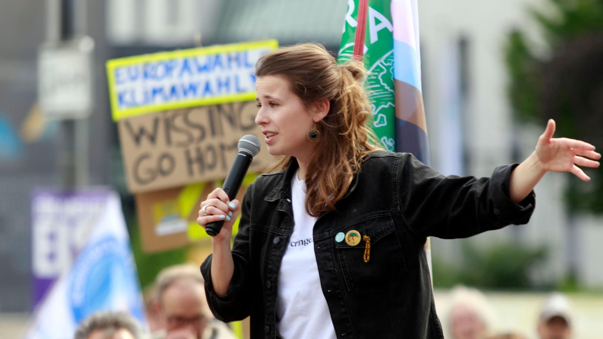 Luisa Neubauer spricht in ein Mikrofon, im Hintergrund Demonstranten.