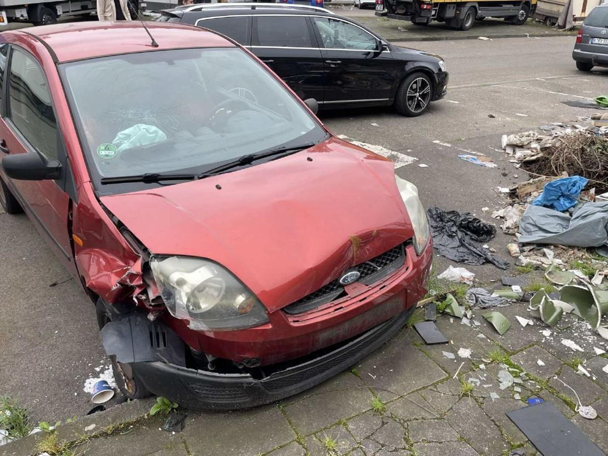 Foto eines kaputten roten Autos der Marke Ford in Köln.