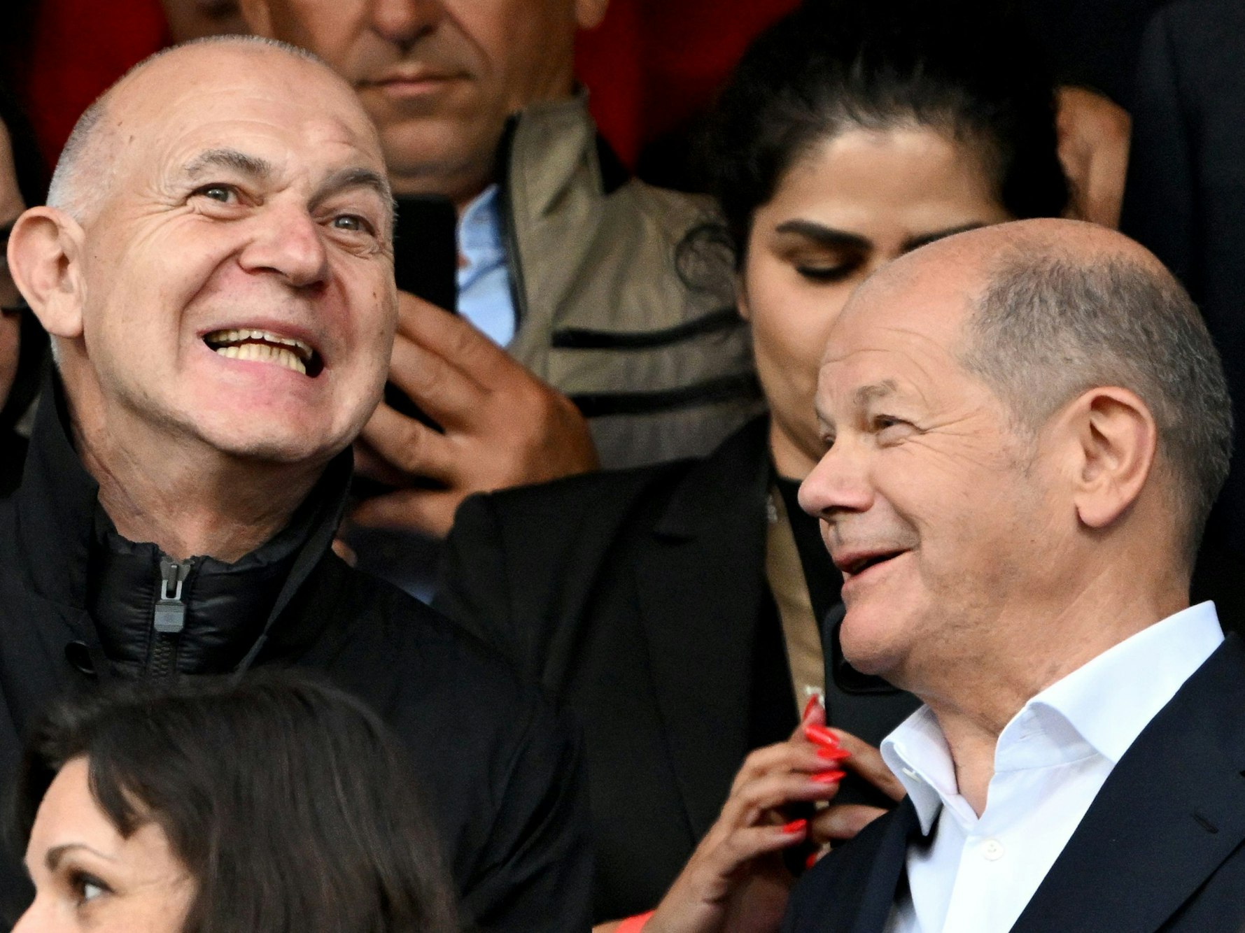 Bundeskanzler Olaf Scholz (SPD, r) steht als Zuschauer auf der Tribüne neben DFB-Präsident Bernd Neuendorf.