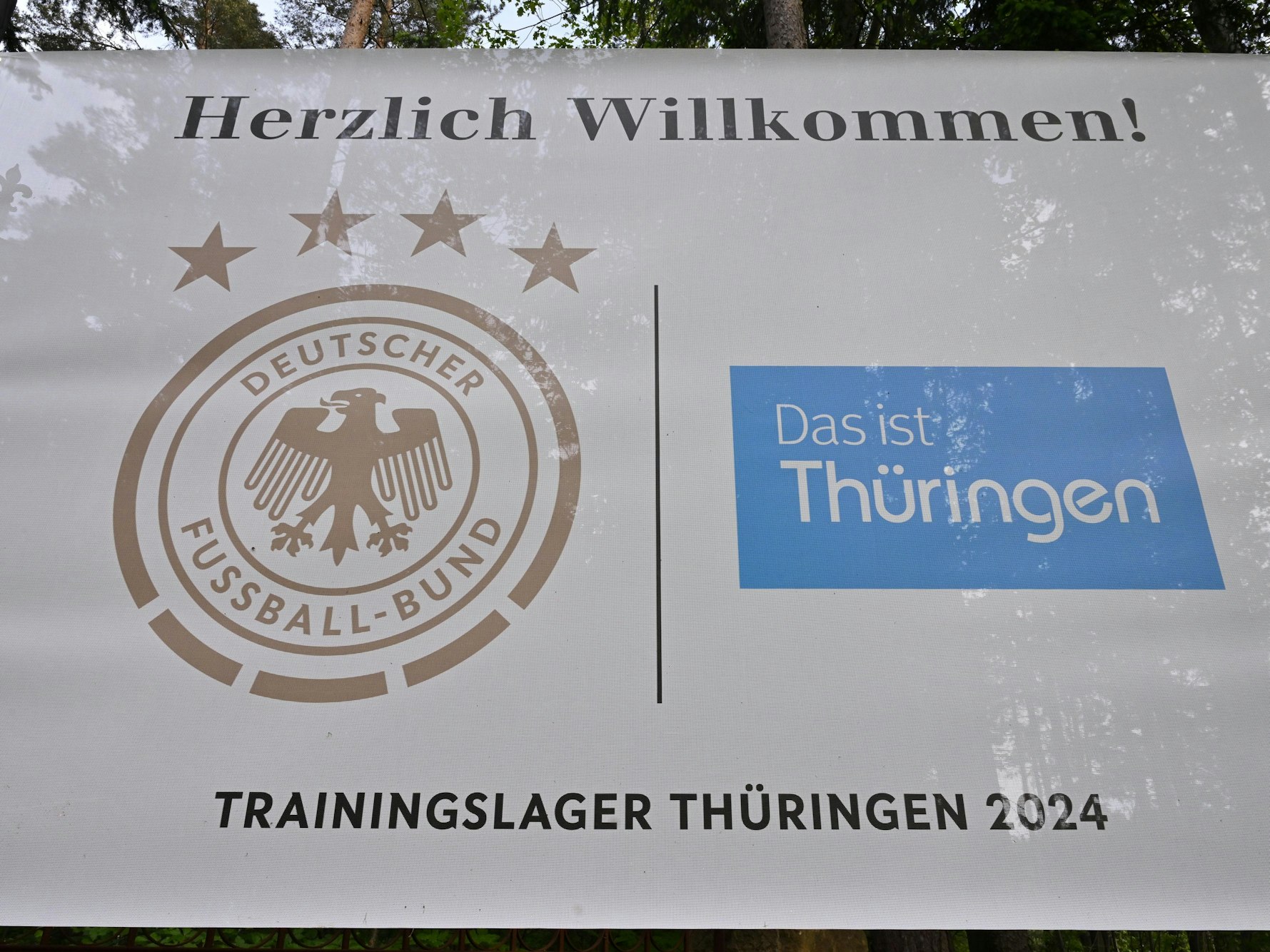 Ein Banner mit dem DFB-Logo und der Aufschrift ·Trainingslager Thüringen 2024· hängt an der Einfahrt zum Spa & Golf Resort Weimarer Land.