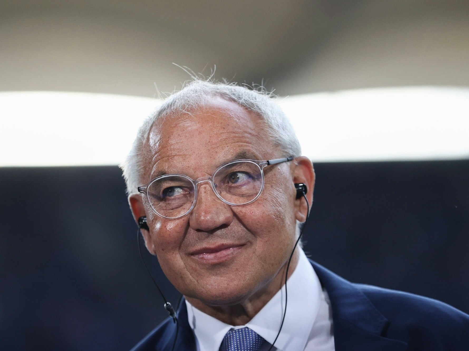 Felix Magath trägt während eines Interviews Kopfhörer im Ohr.