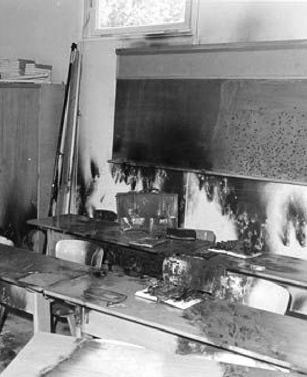Ein verbranntes Klassenzimmer mit Tafel und Schulbänken.