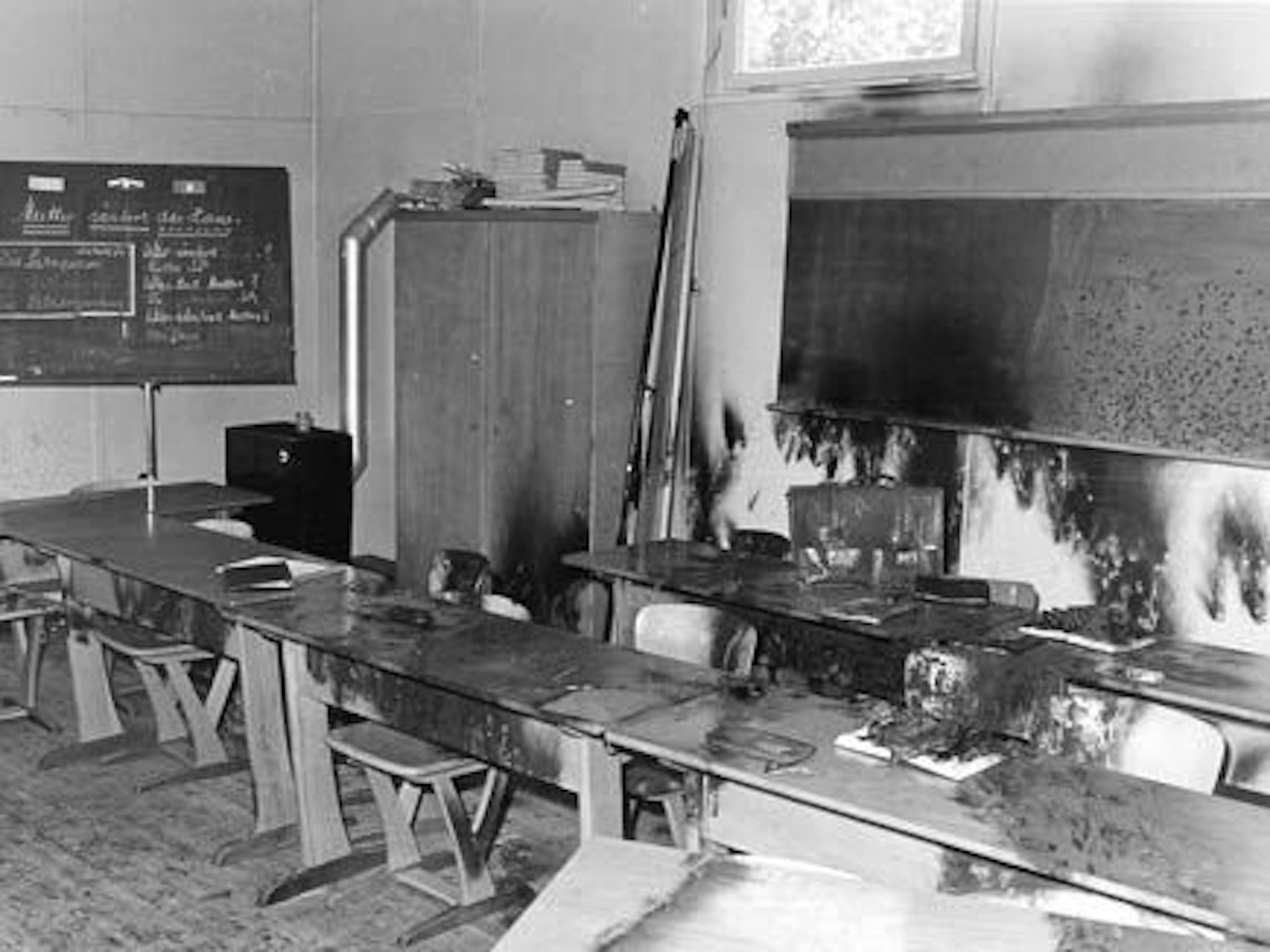 Ein verbranntes Klassenzimmer mit Tafel und Schulbänken.