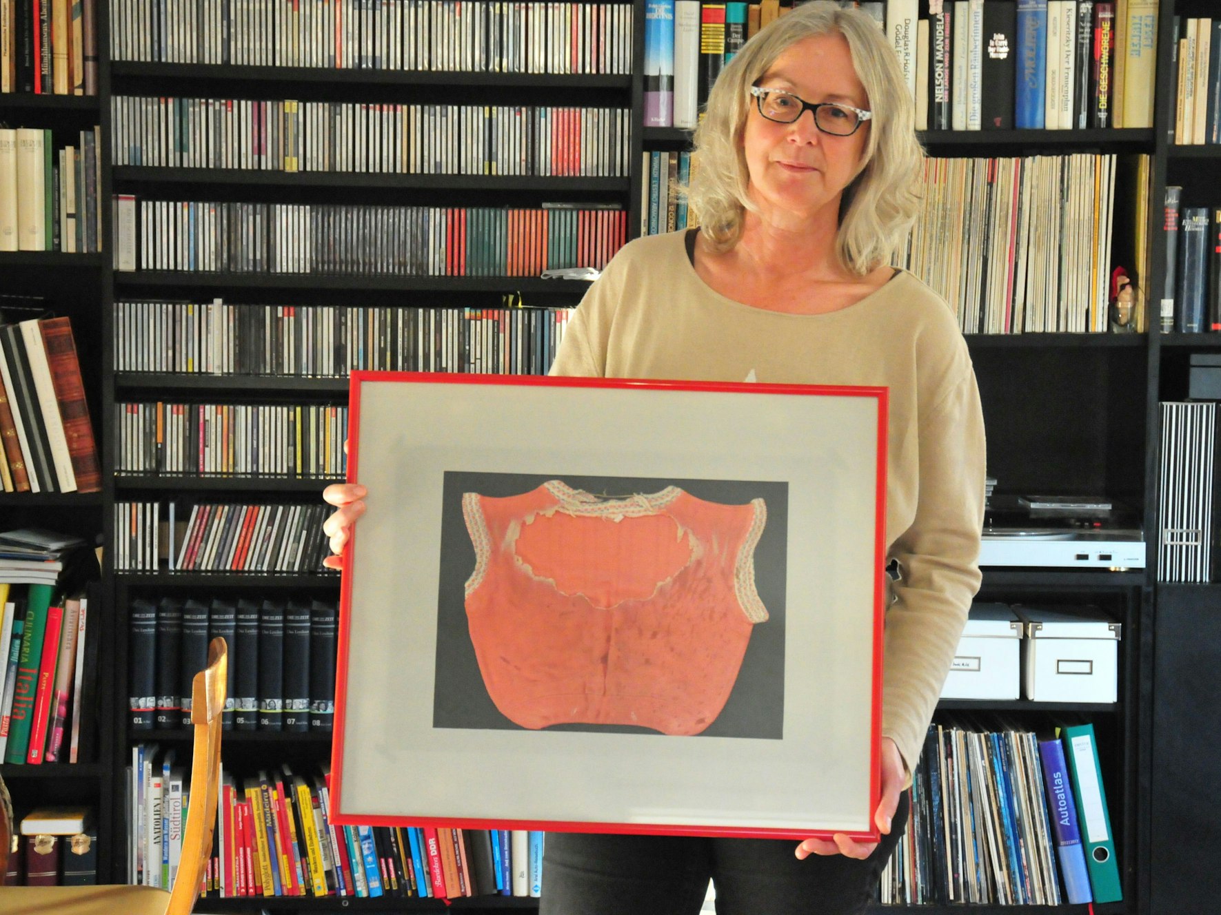 Eine Frau hält ein eingerahmtes T-Shirt.