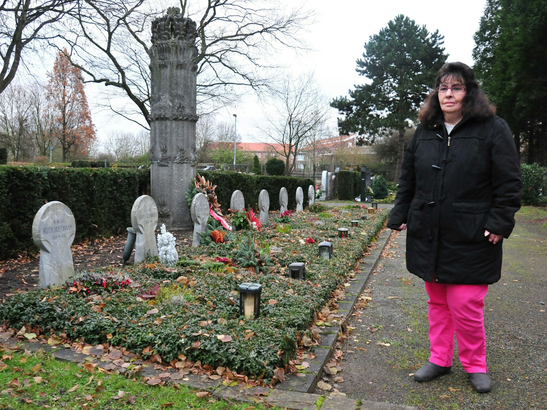 Eine Frau steht einer Reihe von Gräbern.