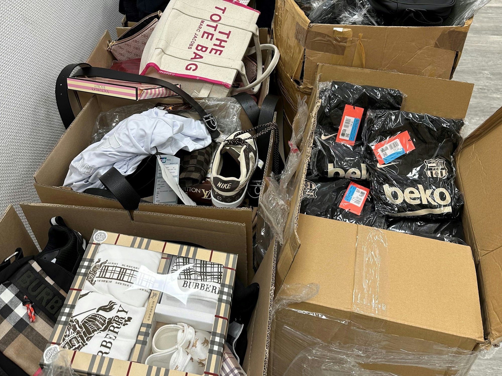 In offenen Kartons sind verpackte Shirts, Taschen, Schuhe, Babykleidung unter anderem von Marc Jacobs und Burberry.