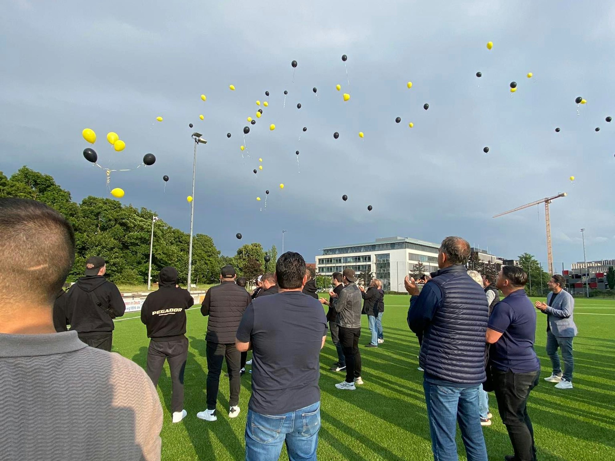 Viele Menschen stehen auf dem Sportplatz in Köln-Deutz und lassen Luftballons aufsteigen.