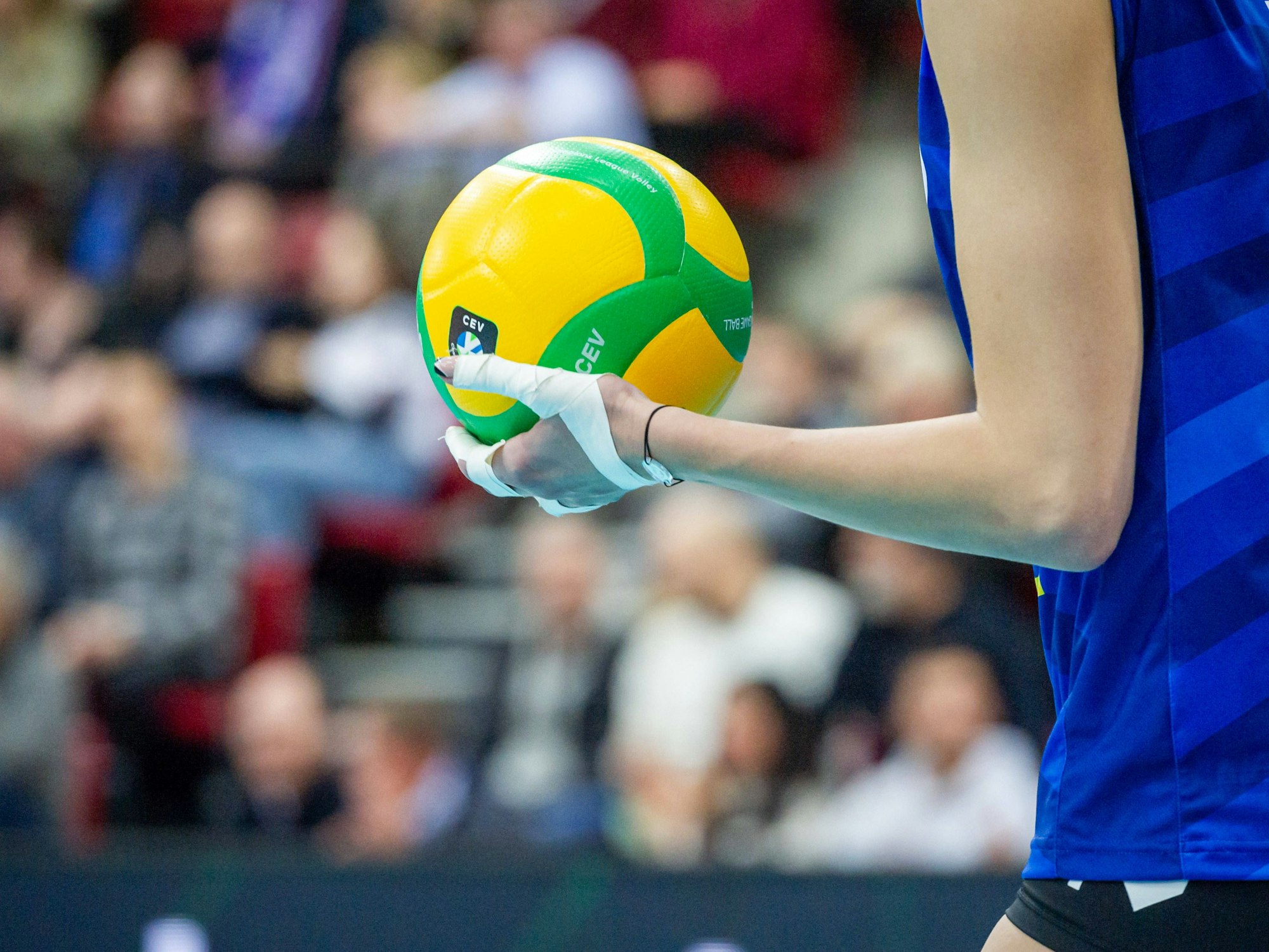 Eine Frau hält einen Volleyball bei einem Spiel in der Hand.