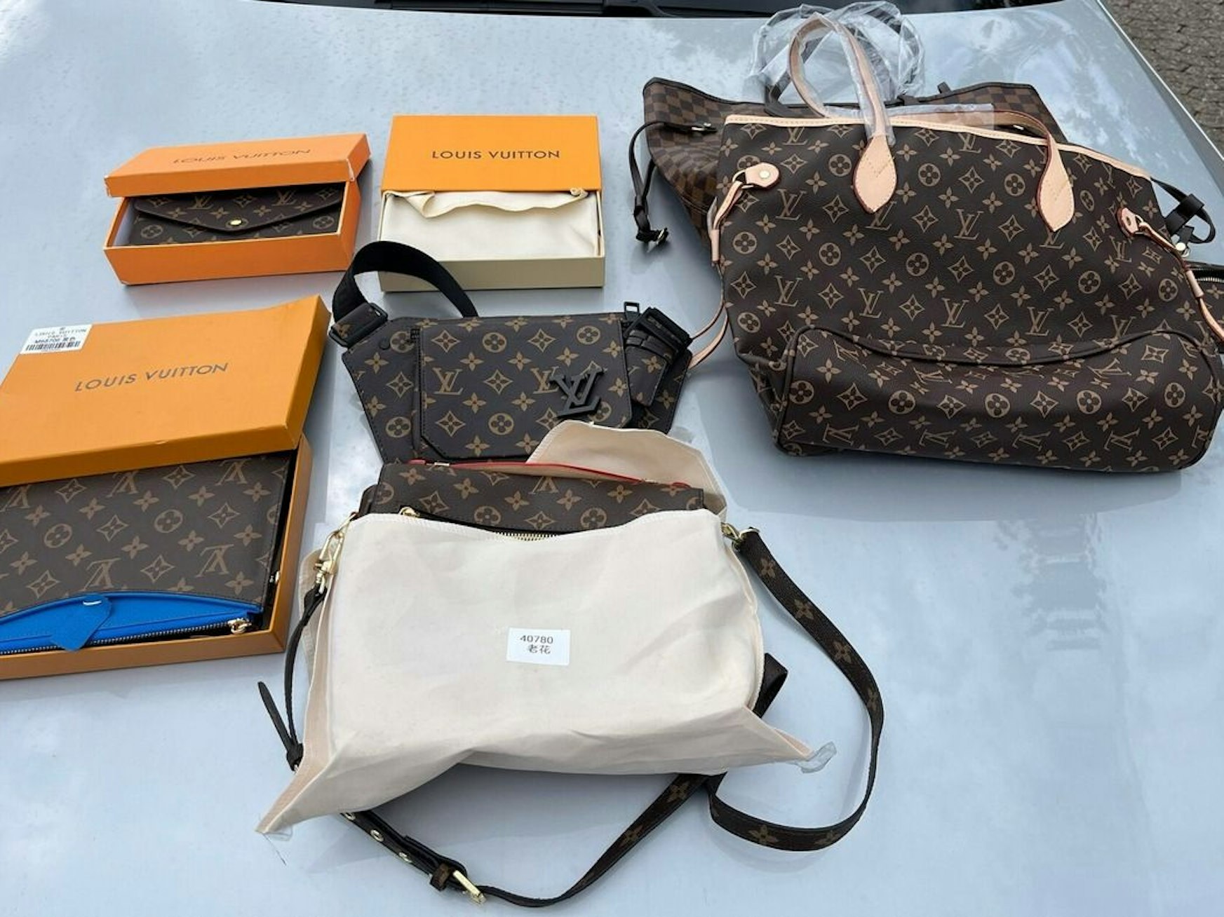 Gefälschte Luxustaschen liegen auf einer Motorhaube.