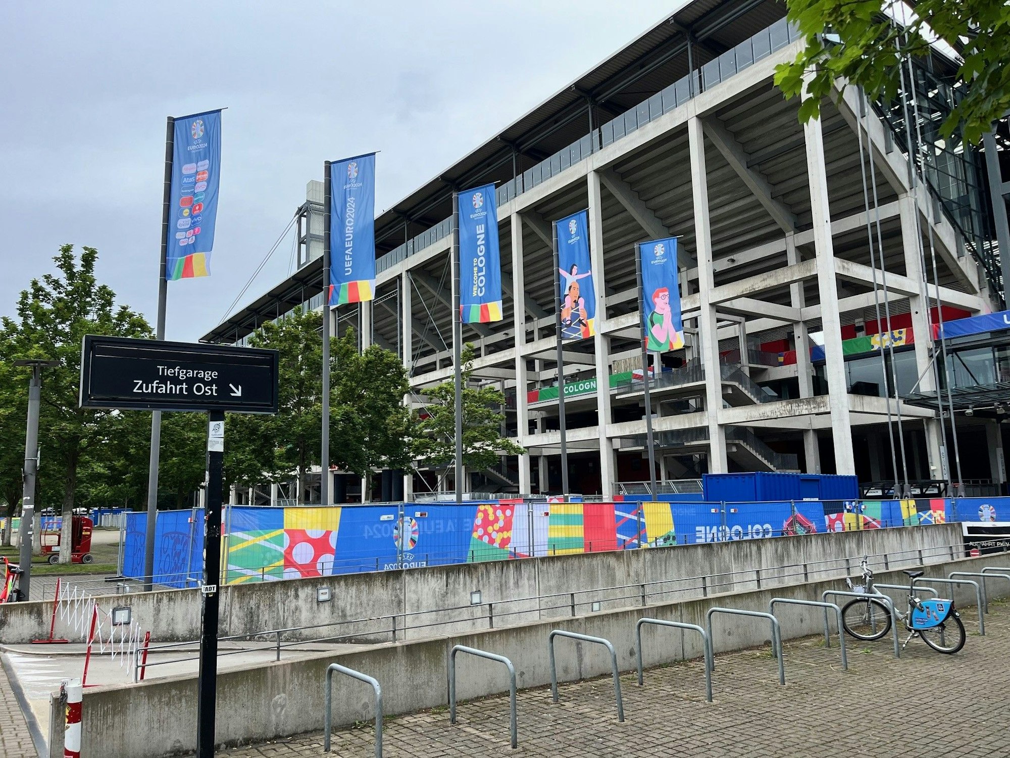 Blick von außen auf das Stadion in Köln, das mit EM-Fahnen in den Farben der Uefa geschmückt ist.