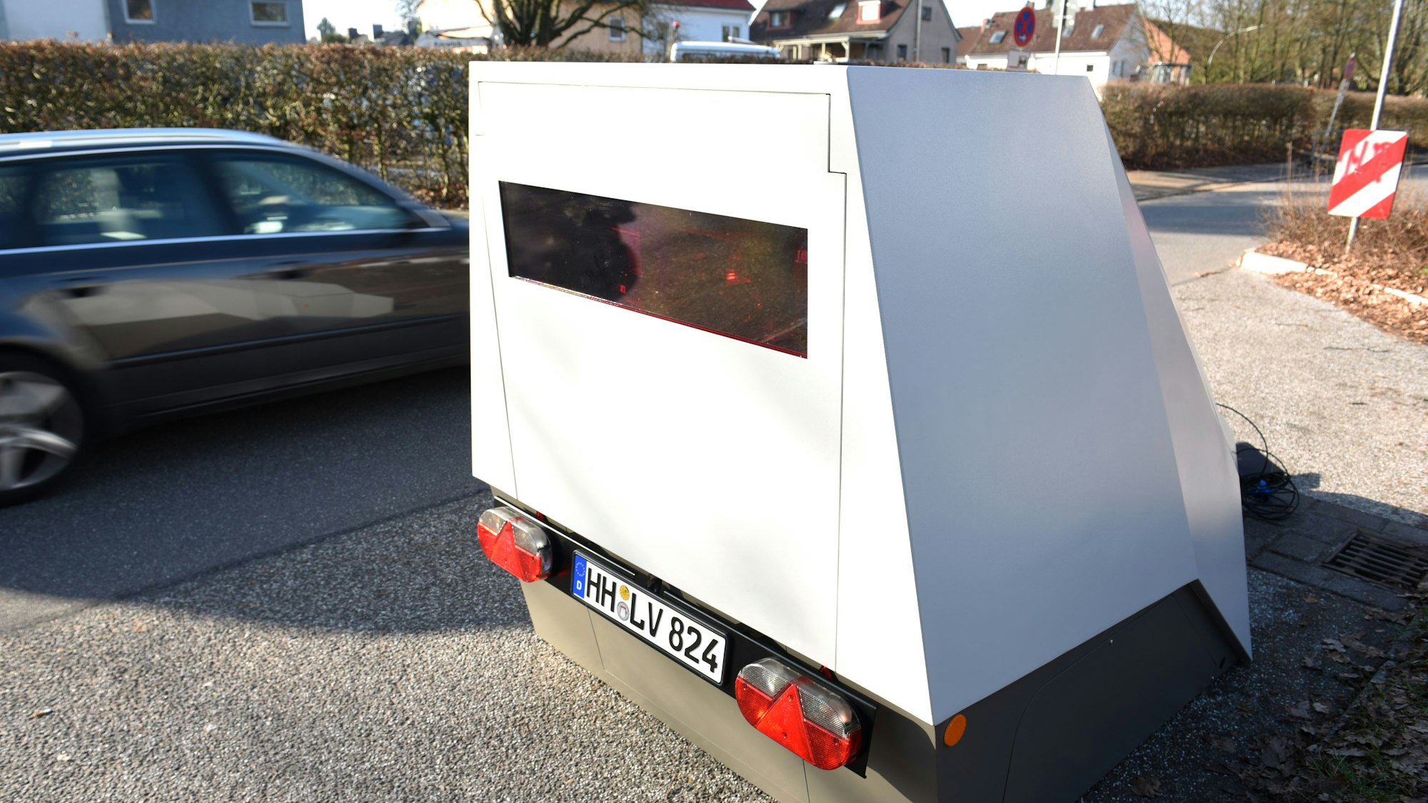 Ein Anhänger zur mobilen Geschwindigkeitsüberwachung steht am Straßenrand.