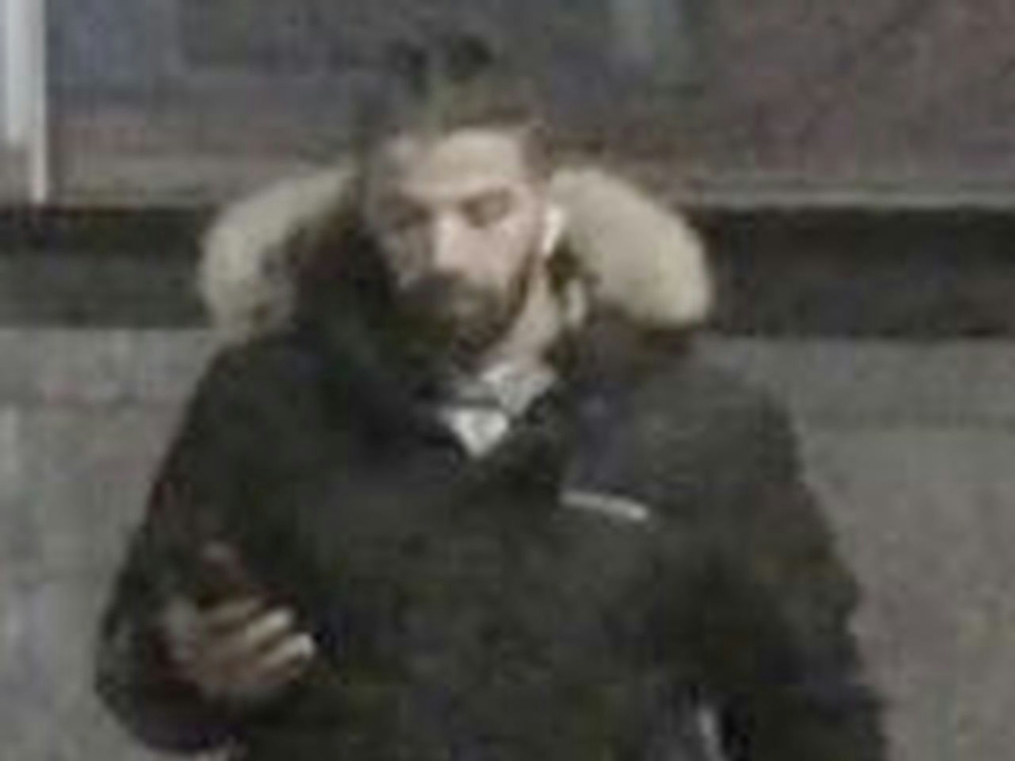 Mann in schwarzer Jacke schaut auf sein Handy, während er geht.