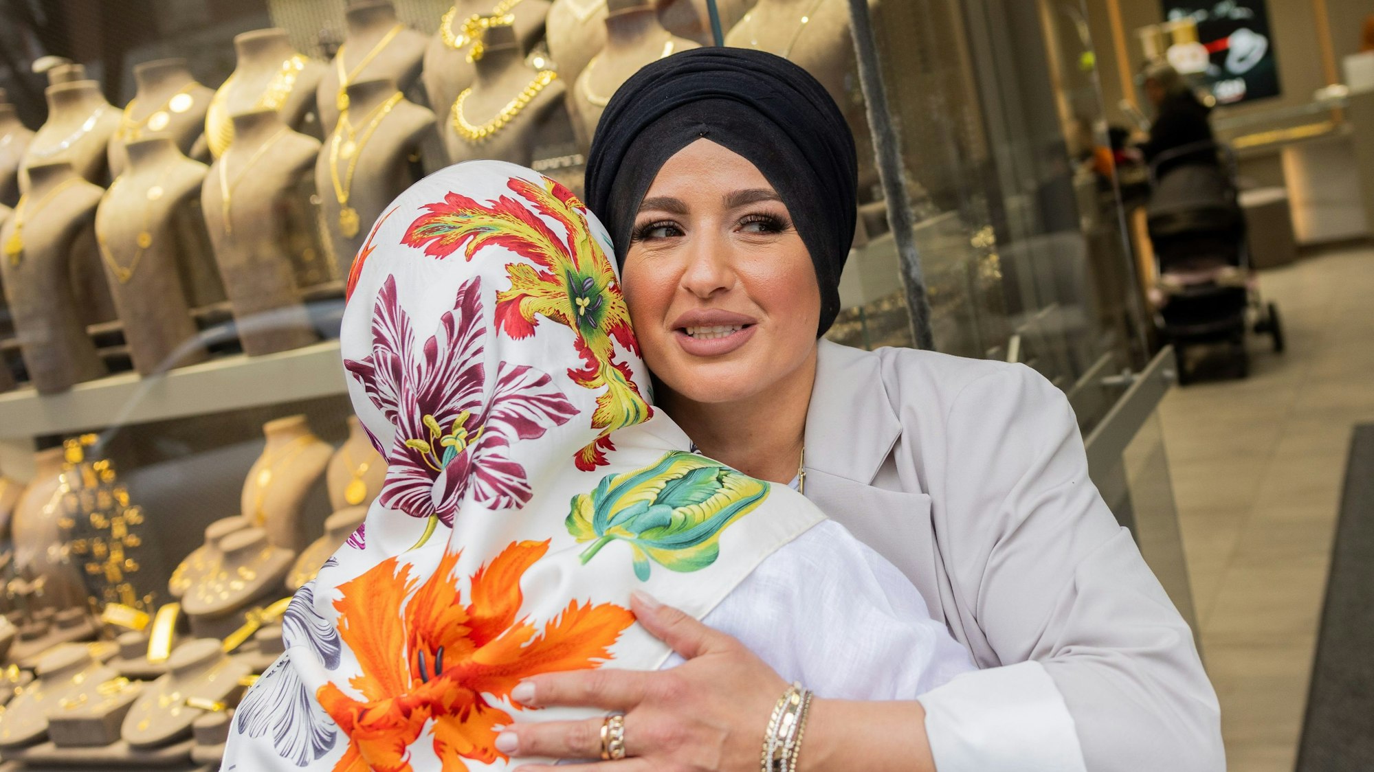 Meral Sahin, Vorsitzende der IG Keupstraße, wird vor dem Eingang eines Juweliers in der Keupstraße von Mitarbeiterin Kübra Karatas (r) begrüßt.