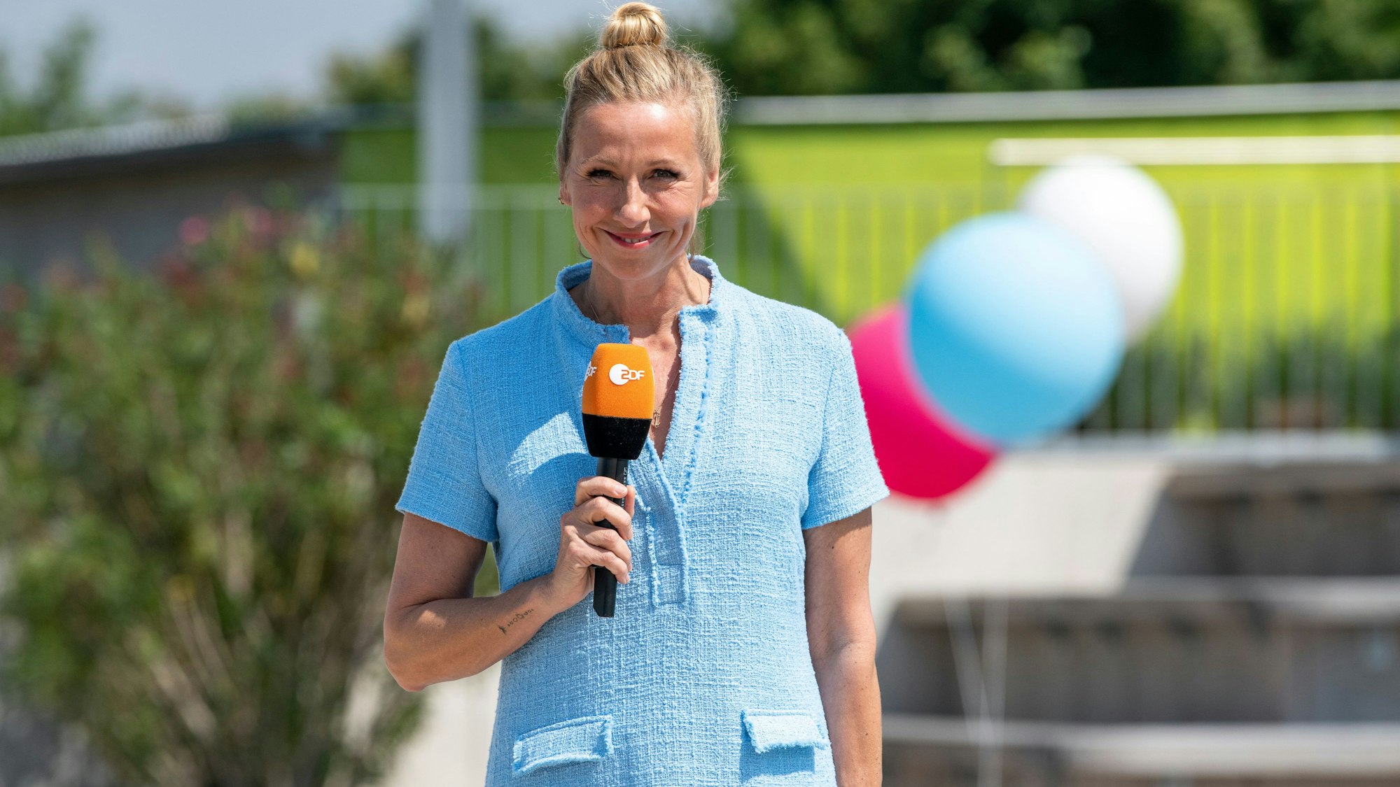 Moderatorin Andrea Kiewel steht im "Fernsehgarten" und lächelt in die Kamera.
