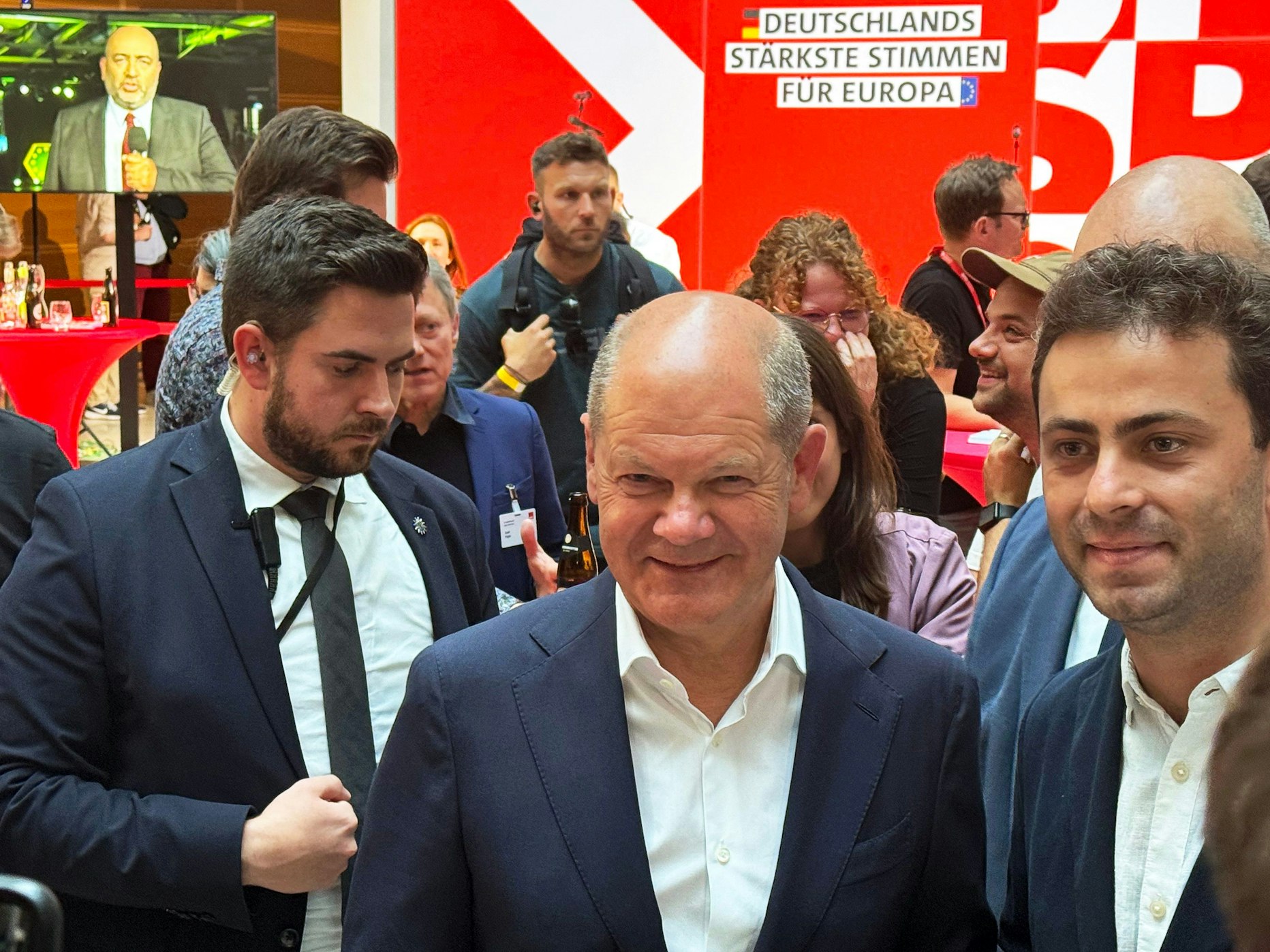 Bundeskanzler Olaf Scholz (SPD, Mitte) reagiert bei der Wahlparty der SPD mit einem Lächeln auf das Ergebnis.