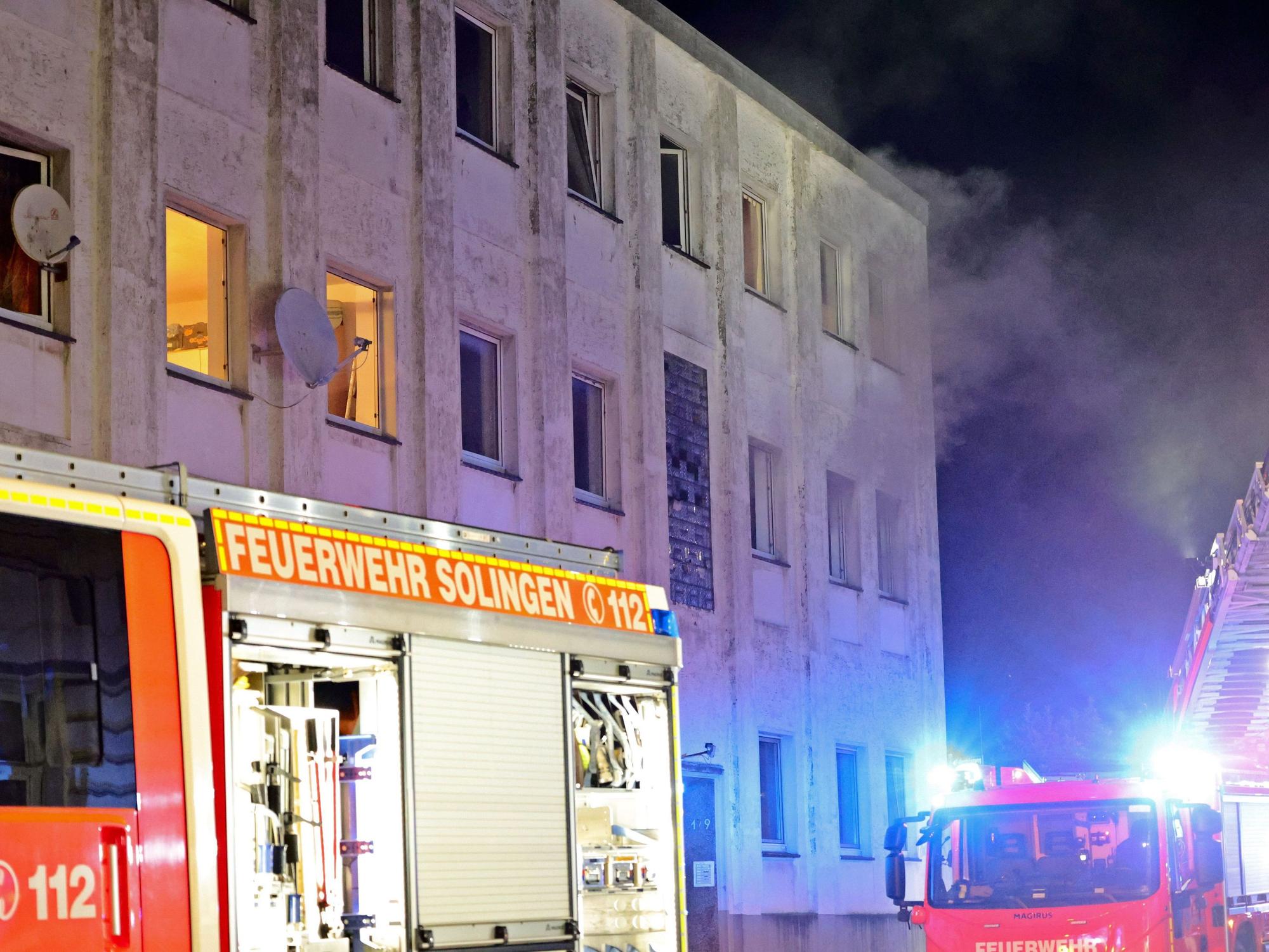 Rauch kommt aus den Fenstern eines Mehrfamilienhauses. Bei dem Hausbrand in Solingen sind etliche Menschen verletzt worden, darunter auch die Besatzung des ersten eingetroffenen Rettungswagen.
