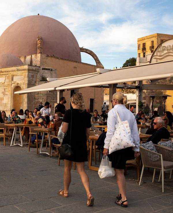 Touristinnen und Touristen spazieren am alten Hafen von Chania auf der Insel Kreta.