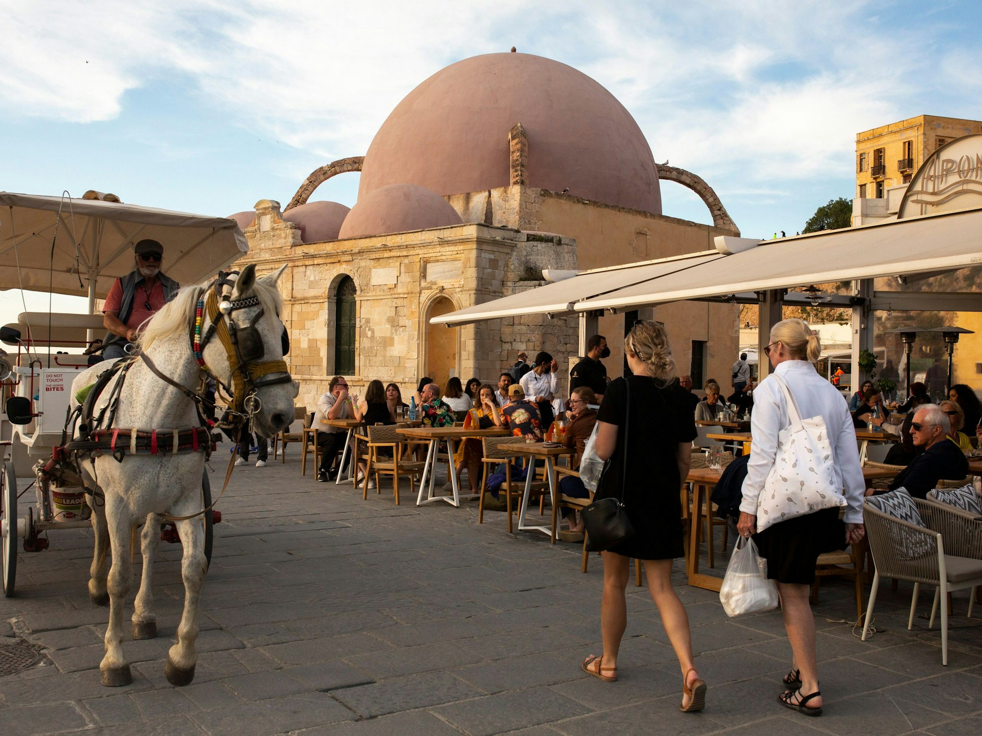 Touristinnen und Touristen spazieren am alten Hafen von Chania auf der Insel Kreta.