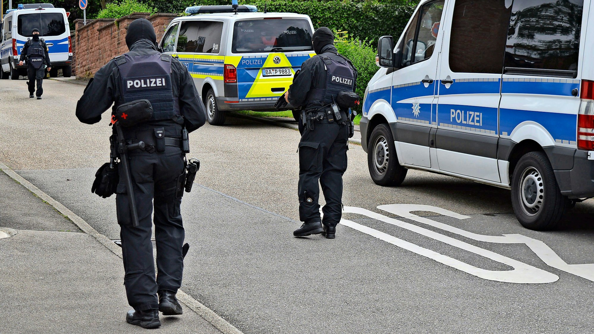 Polizeifahrzeuge und -beamte stehen auf einer Straße.