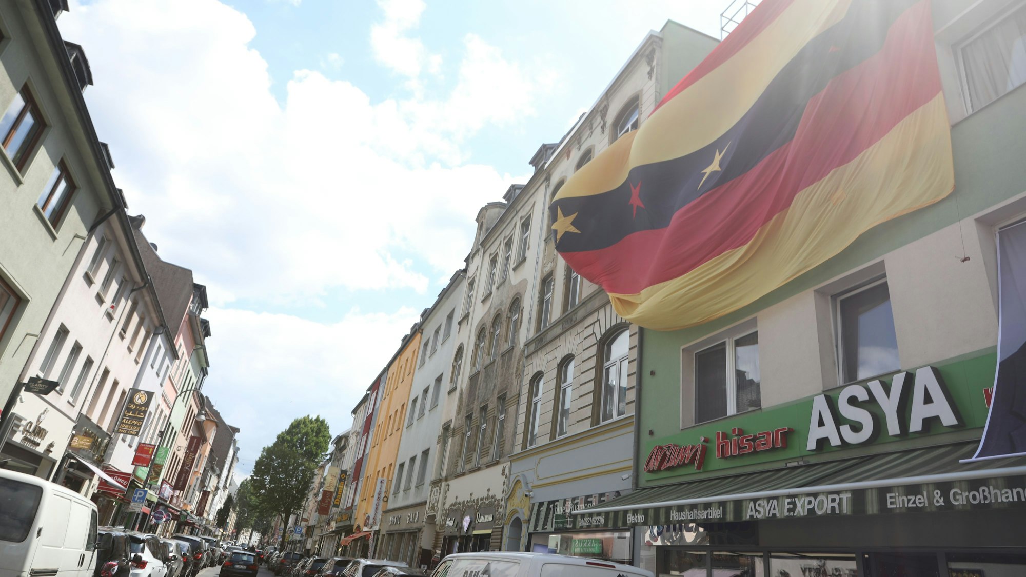 Eine Deutschland-Fahne hängt an einer Fassade an einem Mehrfamilienhaus auf der Keupstraße.