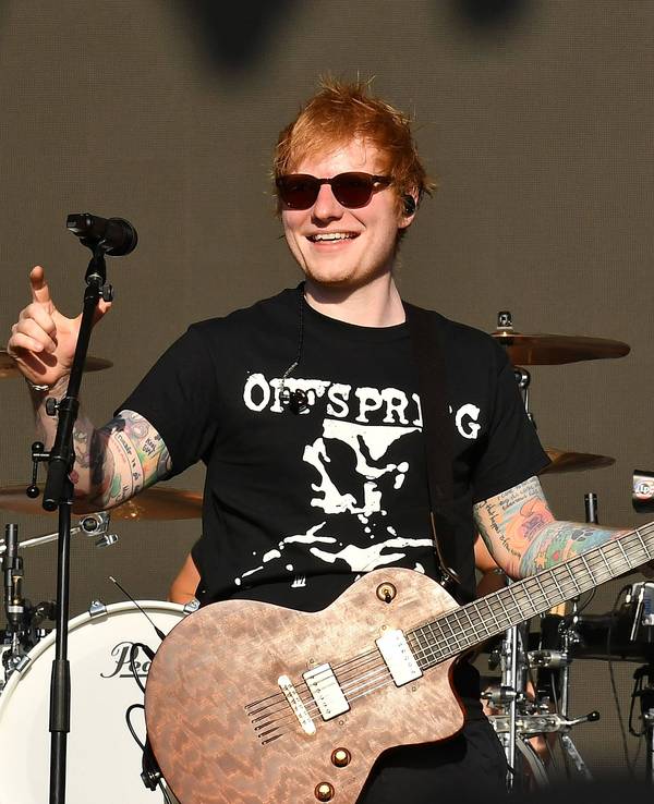 Ed Sheeran hält eine Gitarre in der Hand und steht auf der Bühne.
