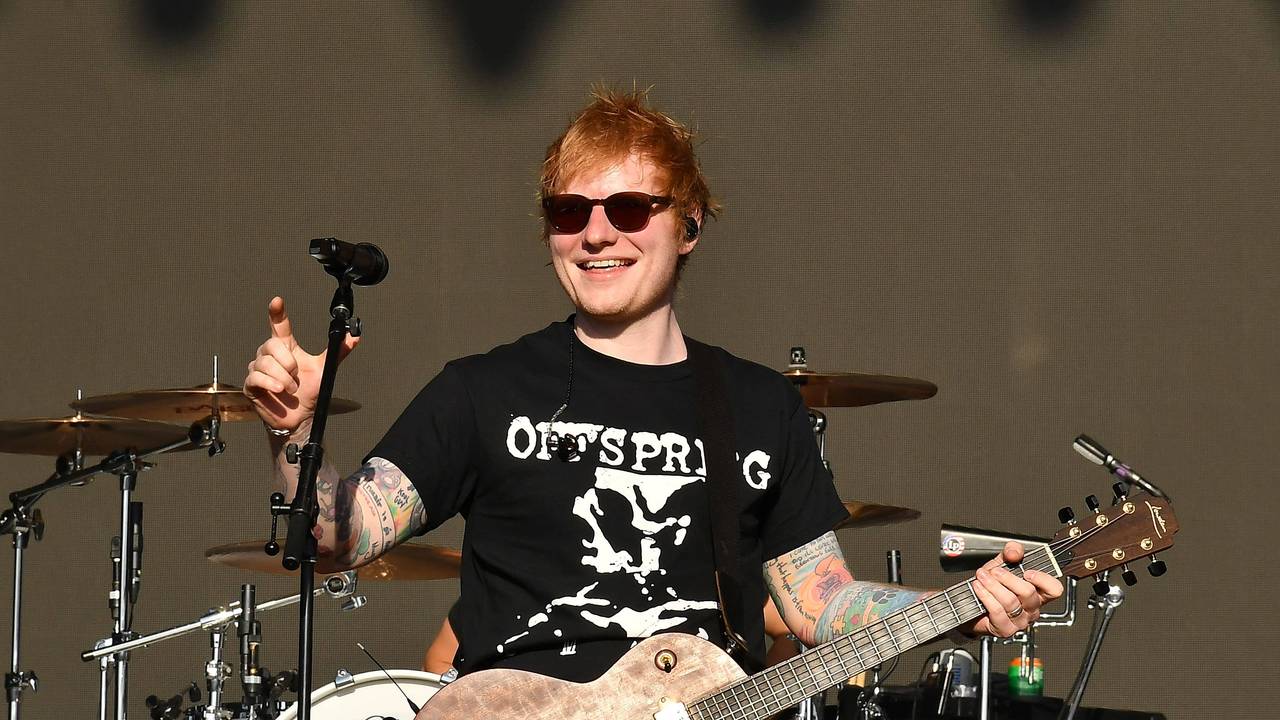 Ed Sheeran hält eine Gitarre in der Hand und steht auf der Bühne.