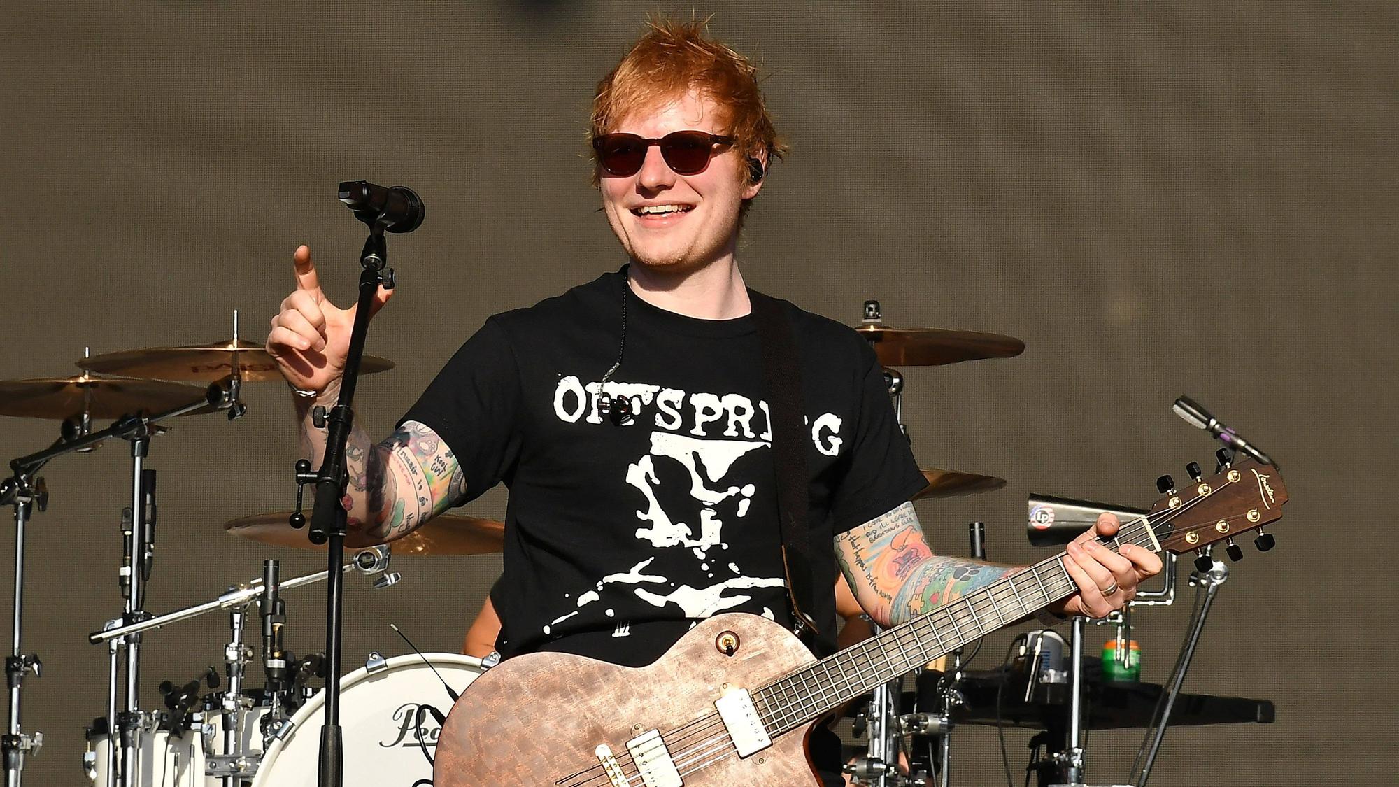 Ed Sheeran hält eine Gitarre in der Hand und steht auf der Bühne.