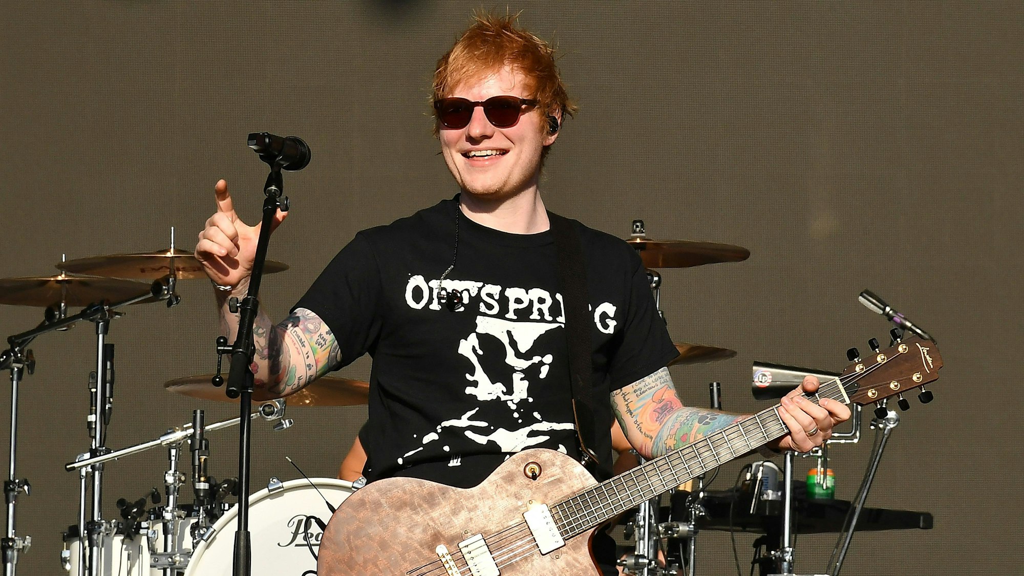 Ed Sheeran hält eine Gitarre in der Hand und steht auf der Bühne.
