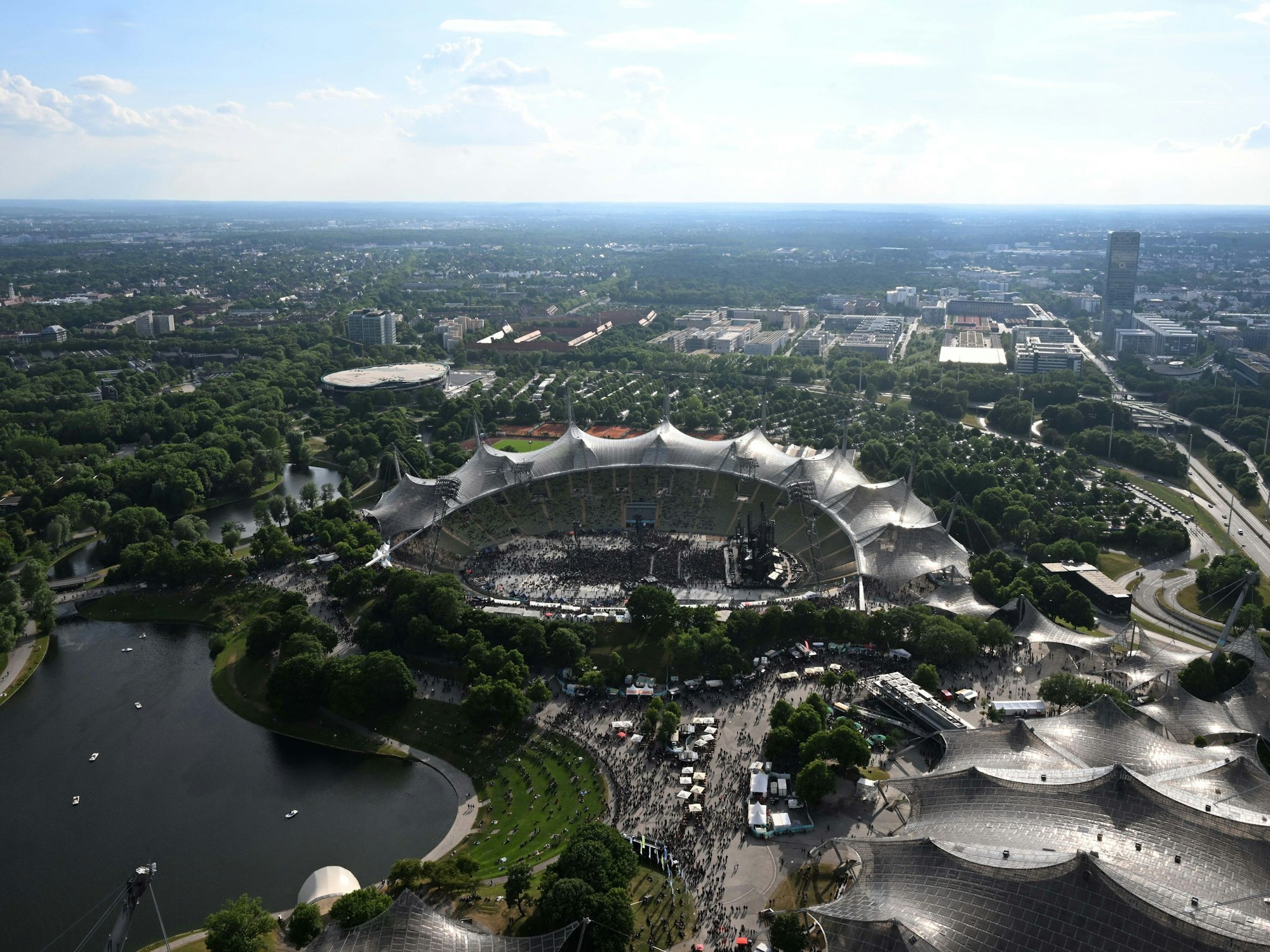 Zuschauer gehen vor Beginn eines Konzertes durch den Olympiapark in Richtung Olympiastadion.