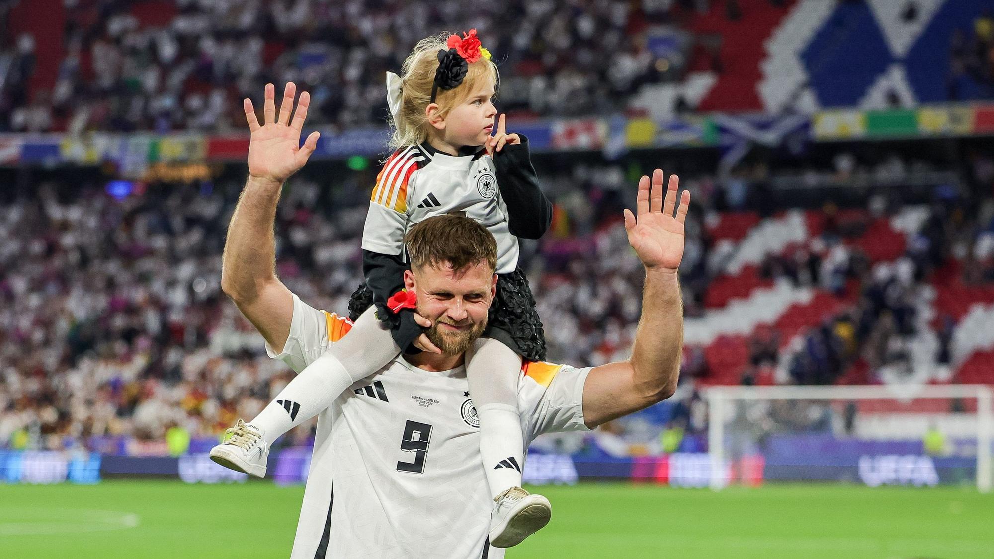 Deutschlands Spieler Niclas Füllkrug trägt nach dem Sieg seine Tochter Emilia durch das Stadion.