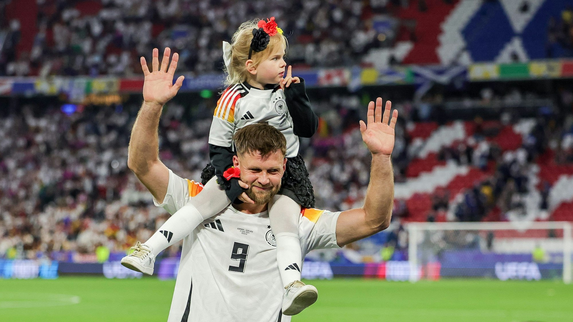 Deutschlands Spieler Niclas Füllkrug trägt nach dem Sieg seine Tochter Emilia durch das Stadion.