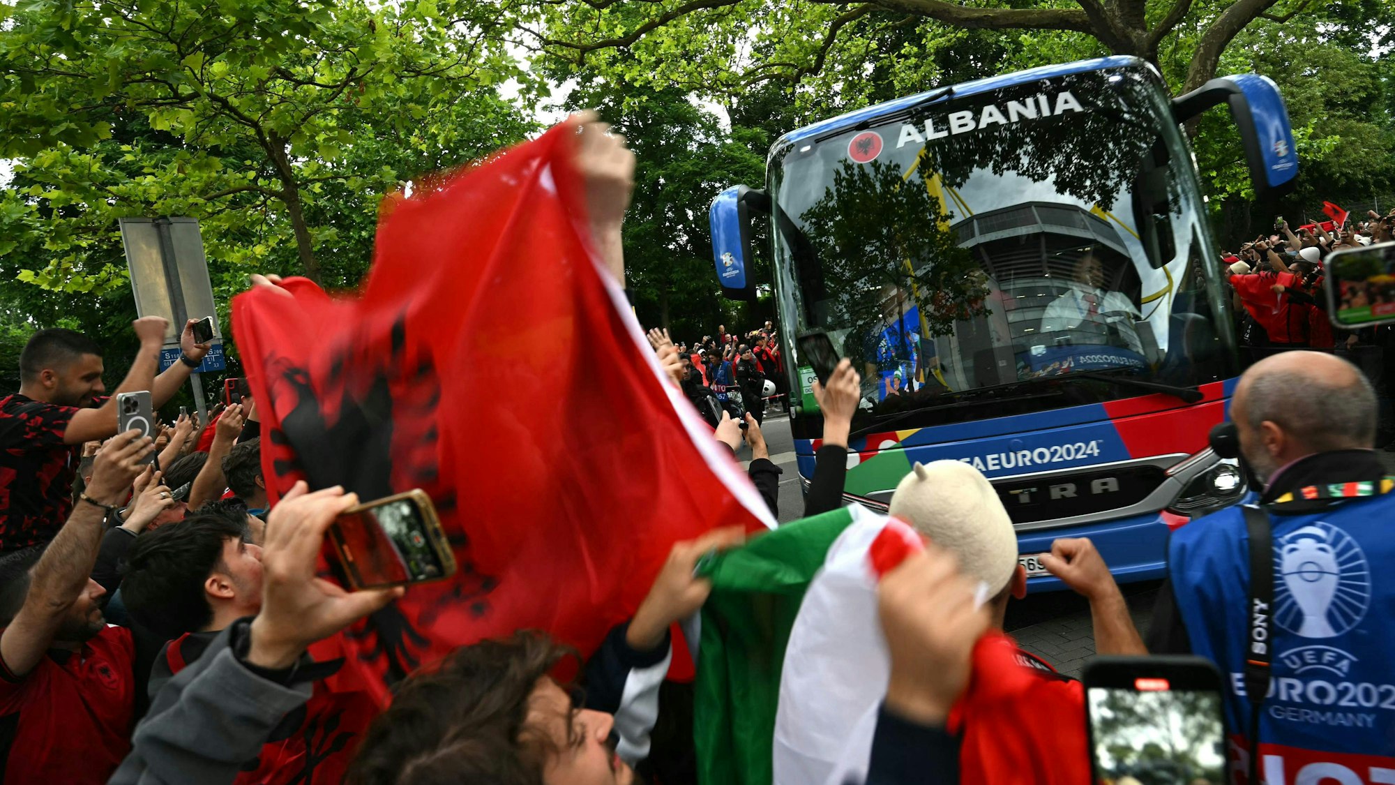 Fans zeigen am 15. Juni 2024 albanische und italienische Flaggen, während der albanische Mannschaftsbus am Stadion ankommt.