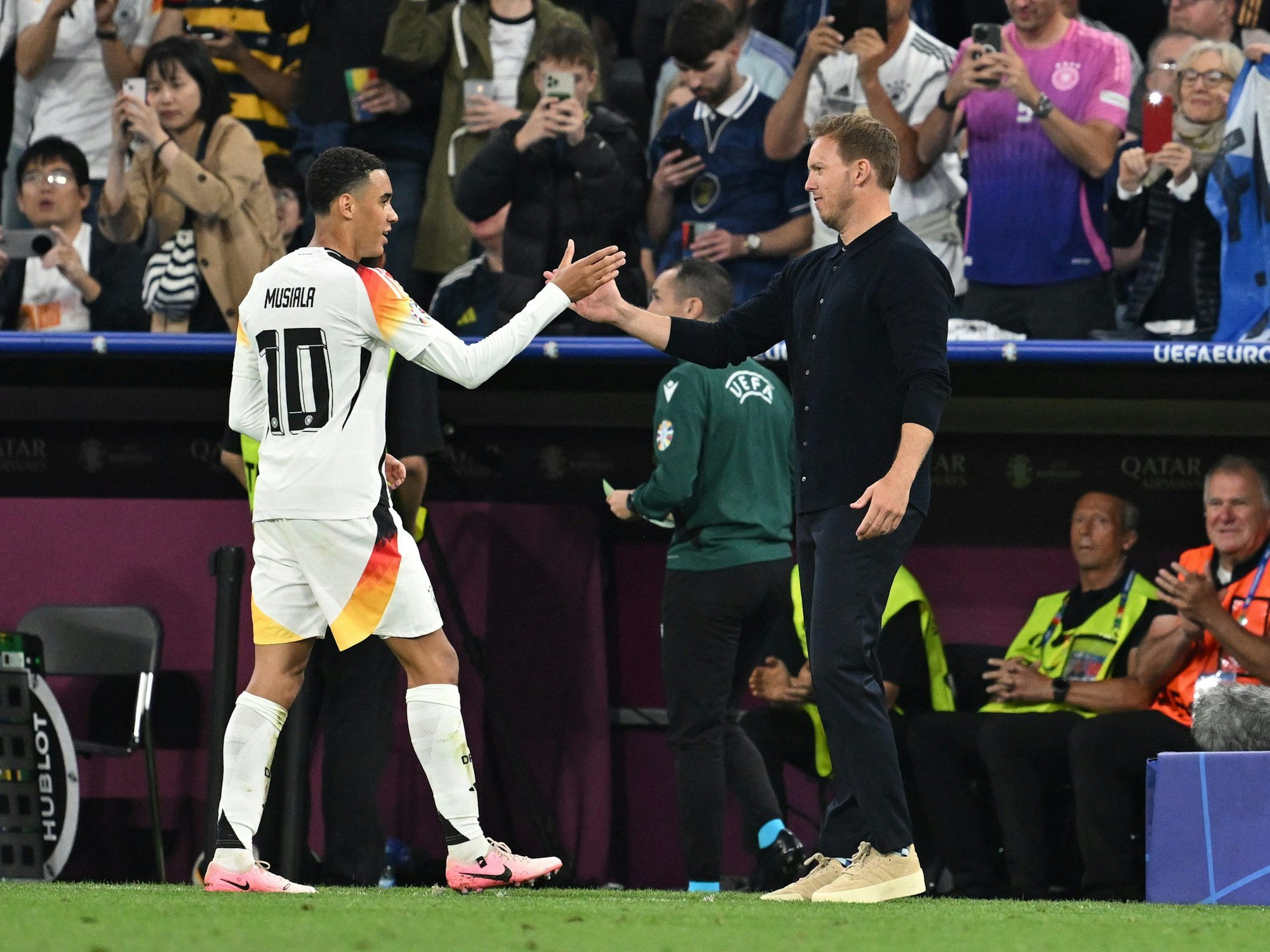 Jamal Musiala klatscht nach seiner Auswechslung mit Deutschlands Trainer Julian Nagelsmann ab.
