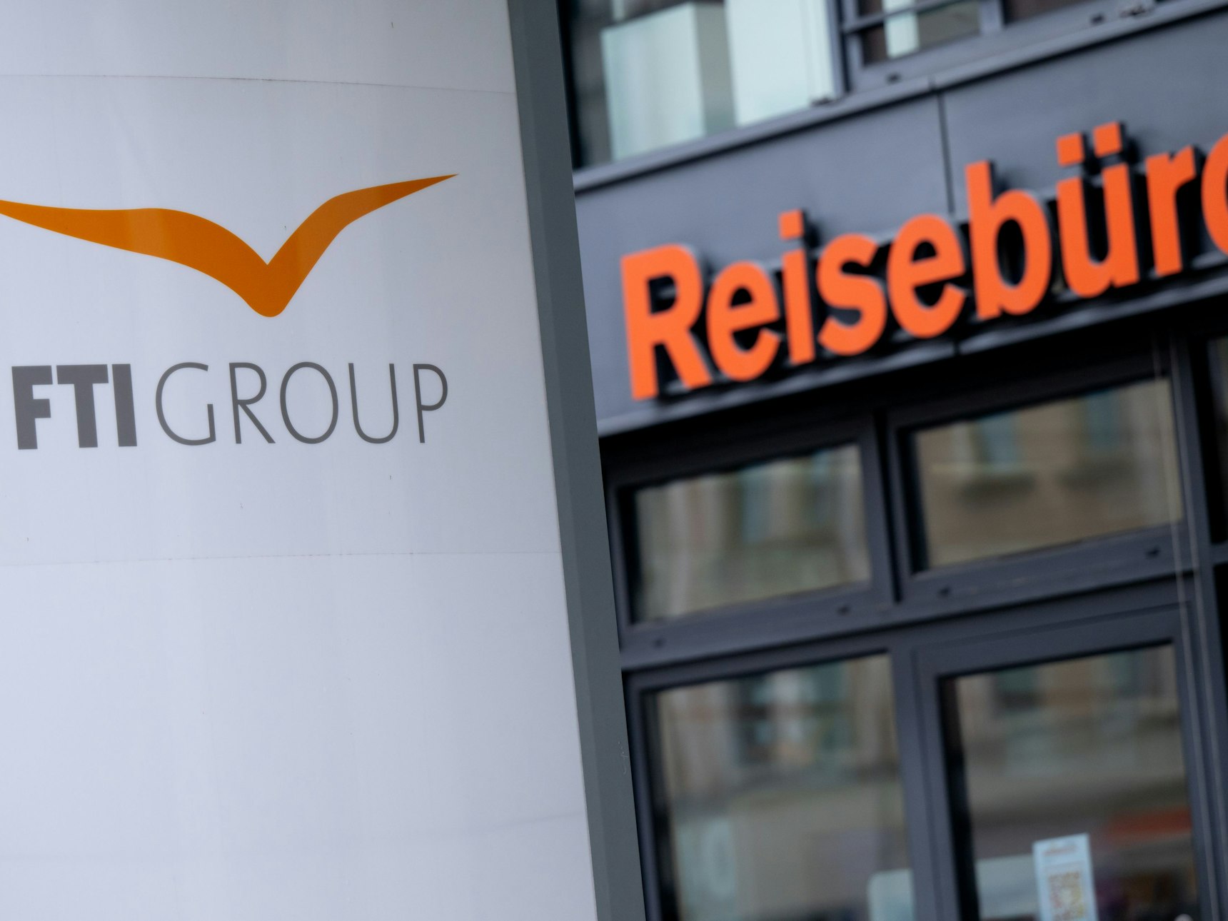 Das Logo des Reiseveranstalters FTI vor einem Reisebüro